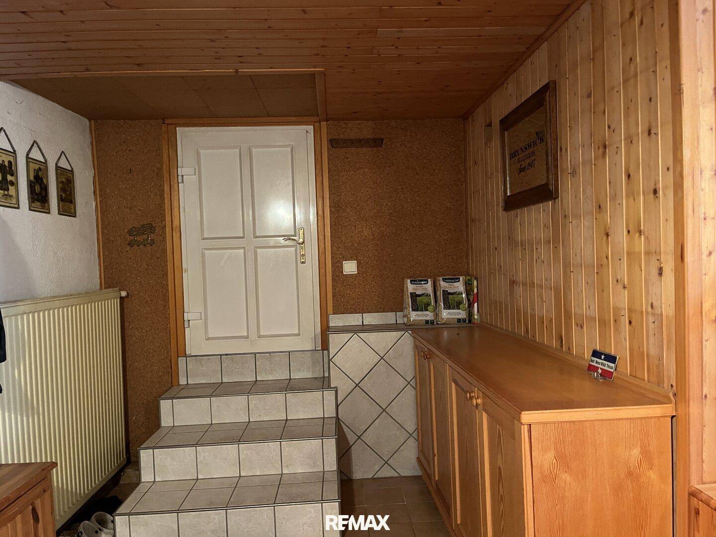 Kellerzugang mit gefliester Treppe, Holztäfelung und Stauraum, funktional und ordentlich.