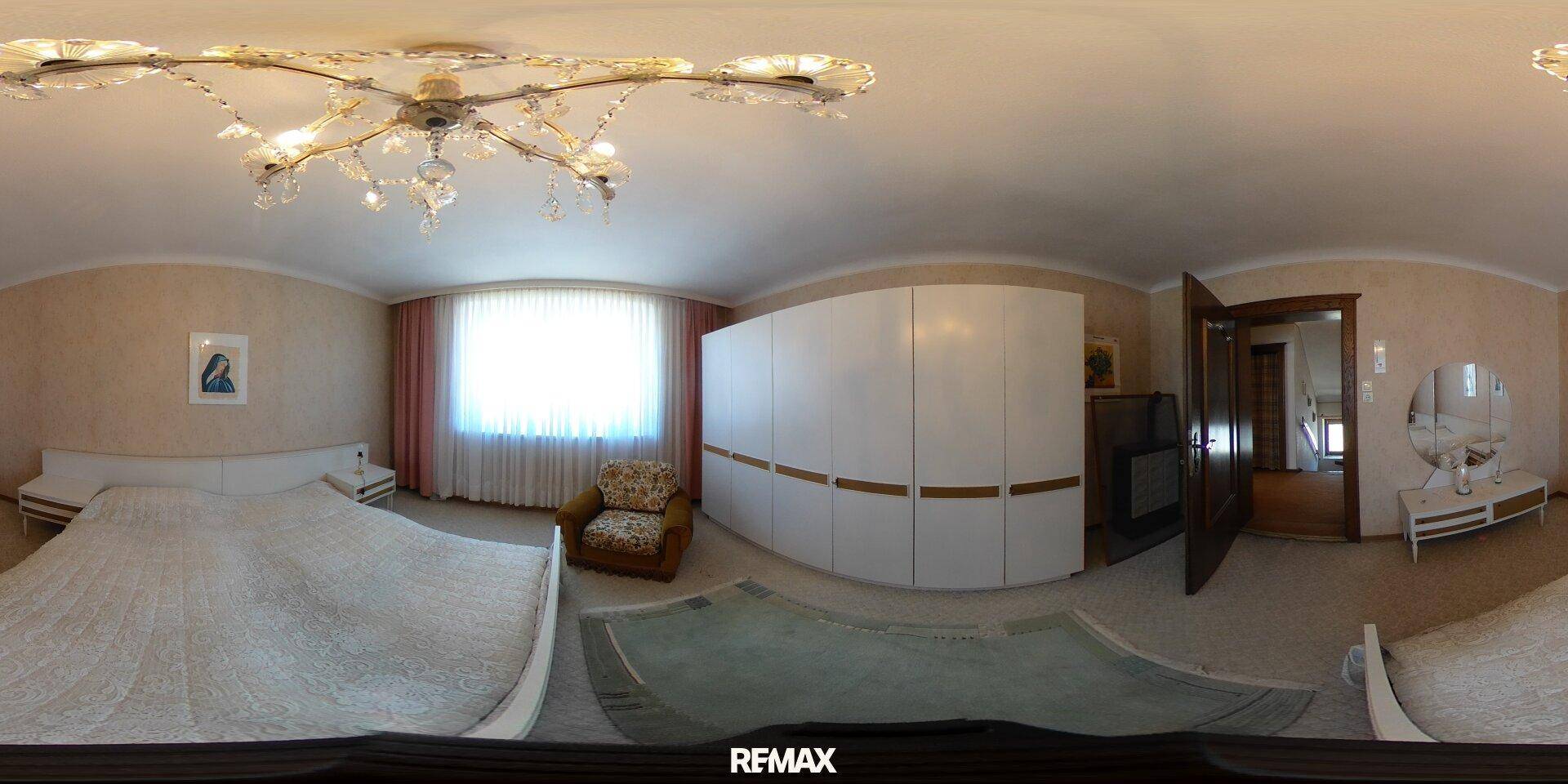 Schlafzimmer mit großem Bett, weißem Kleiderschrank und gemusterter Tapete.