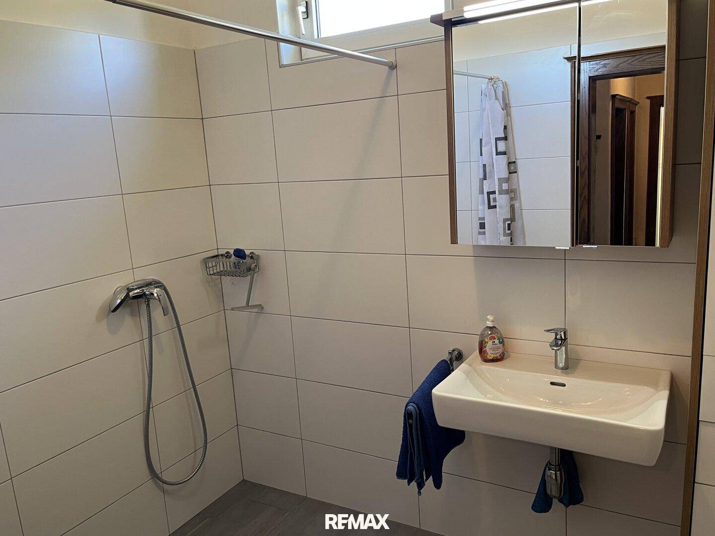 Modernisiertes Badezimmer mit ebenerdiger Dusche, Einzelwaschbecken und Fenster für Tageslicht.
