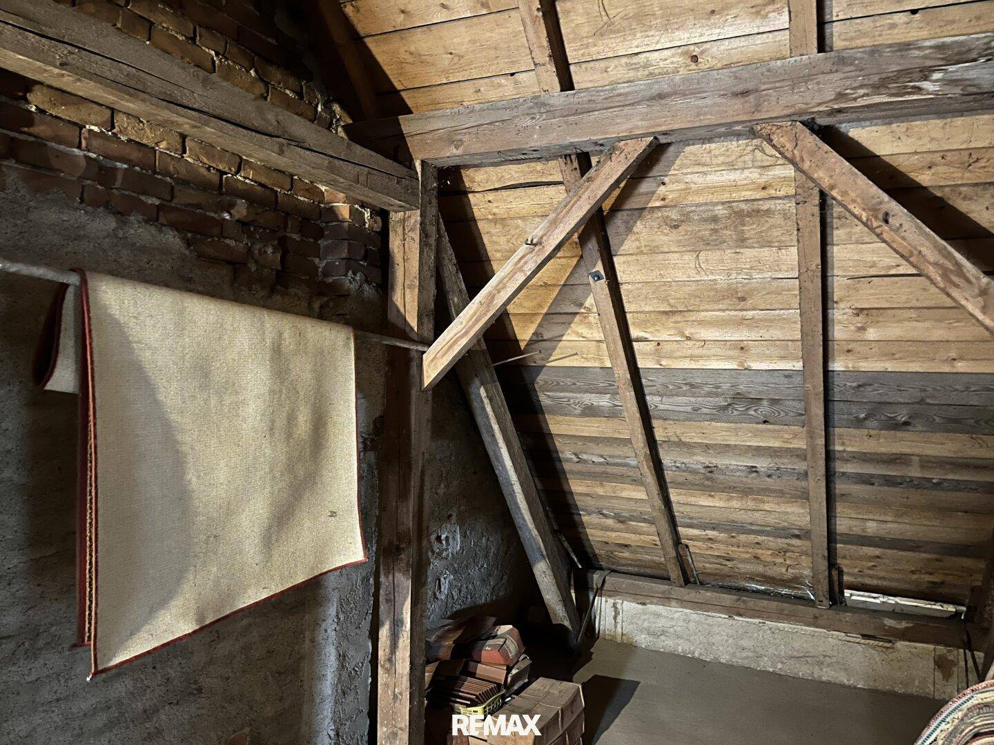 Rustikaler Dachboden mit Holzbalken und Holzverkleidung, ideal als zusätzlicher Stauraum.