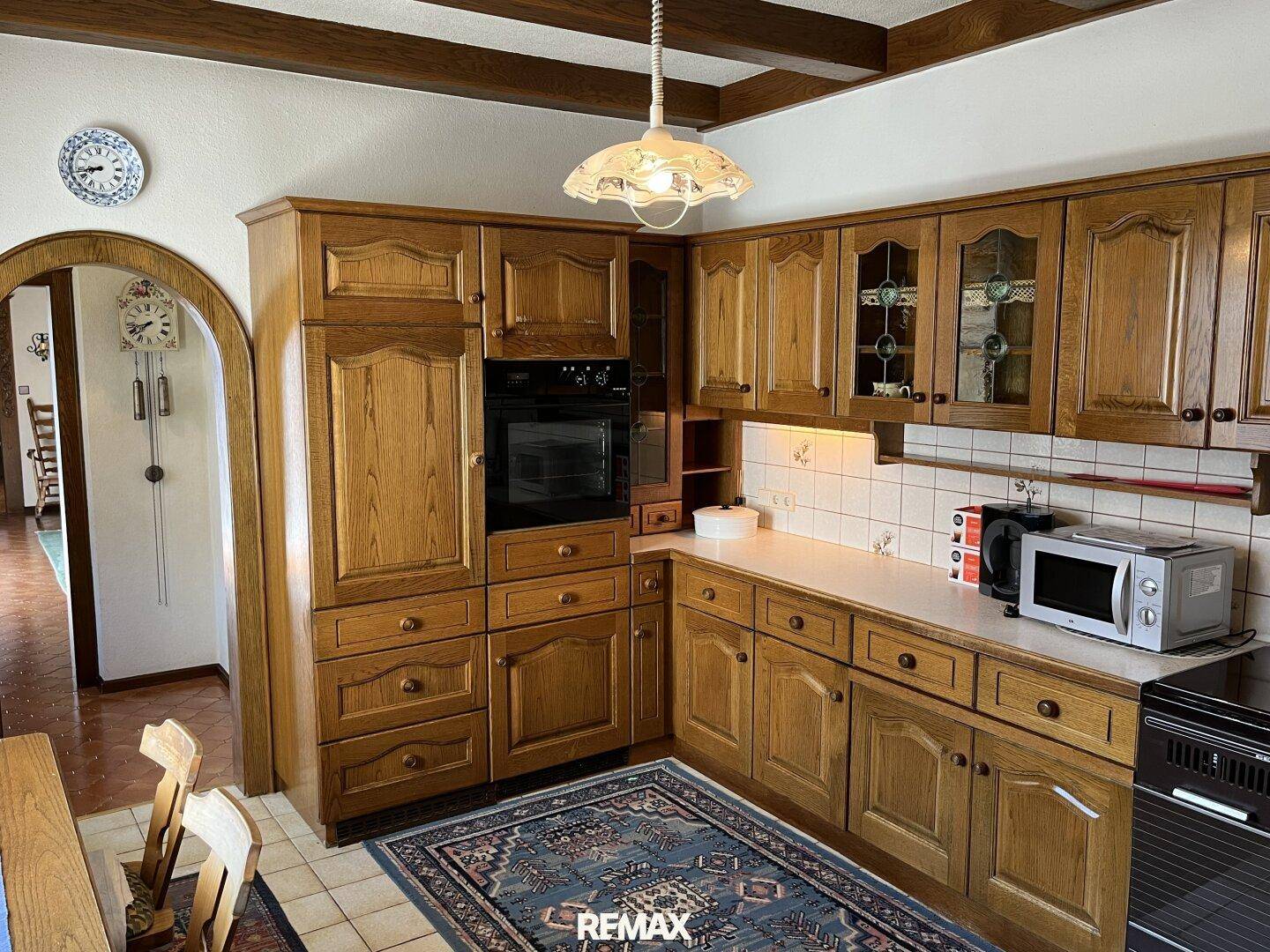 Traditionelle Holzküche mit Einbauschränken, integriertem Backofen und gefliestem Boden.