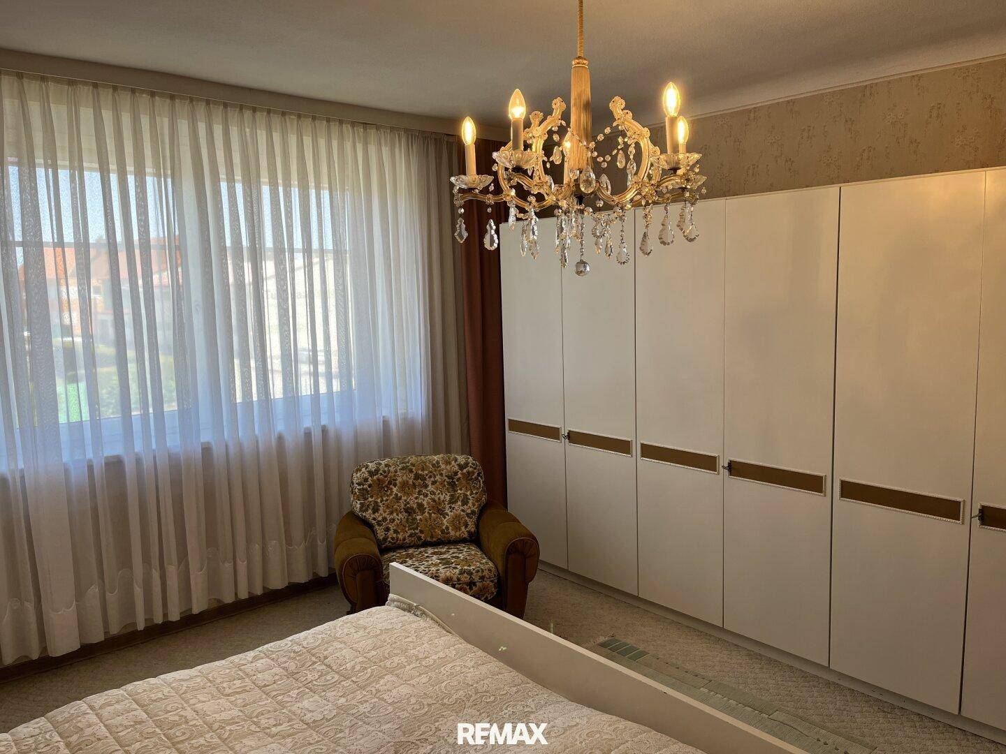 Geräumiges Schlafzimmer mit großen weißen Kleiderschränken, Kronleuchter und Teppichboden.