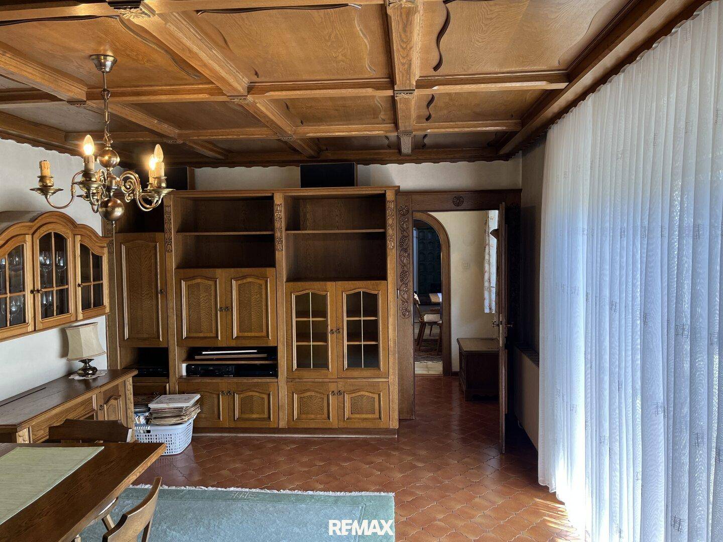 Wohnzimmer im traditionellen Stil mit Holzbalkendecke, großer Schrankwand und Terrakotta-Boden.