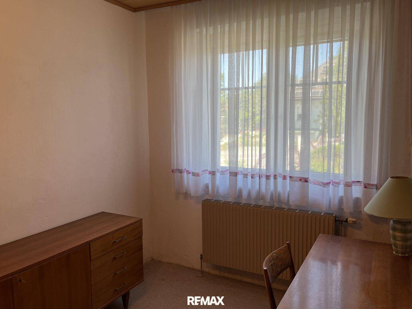 Heller Raum mit Fenster, Heizkörper und einfacher Einrichtung, ideal als Schlaf- oder Arbeitszimmer.