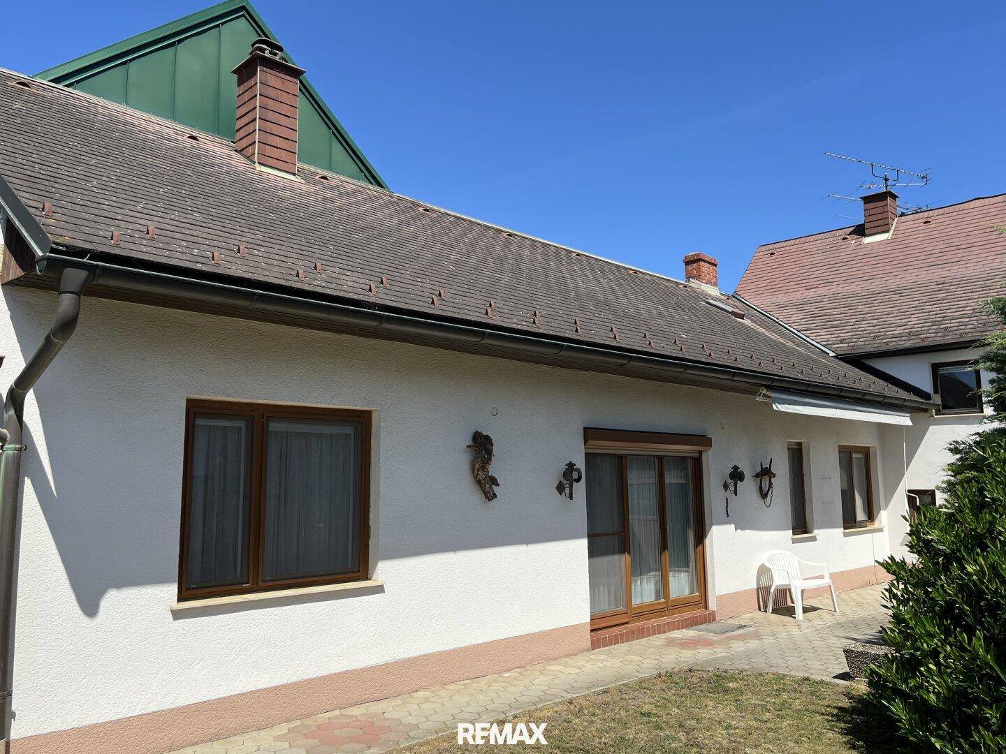 Seitenansicht des Hauses mit einer kleinen Rasenfläche und einem gepflasterten Bereich.