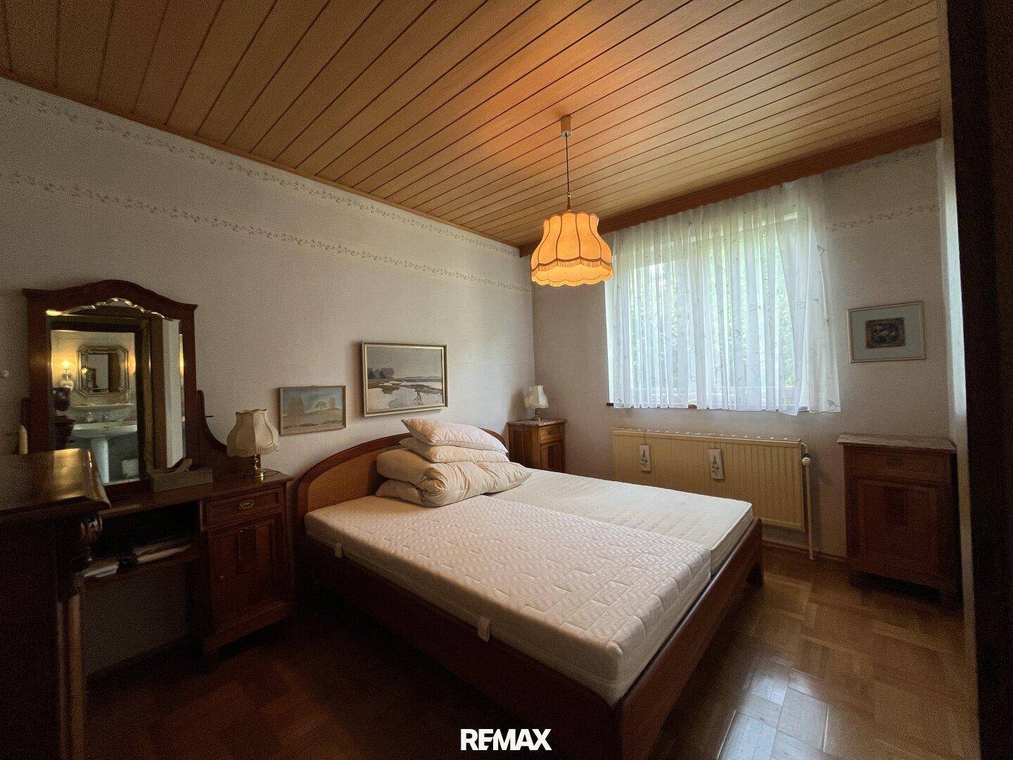 Schlafzimmer mit Holzdecke, Parkettboden und traditionellen Holzmöbeln, hell und gemütlich.