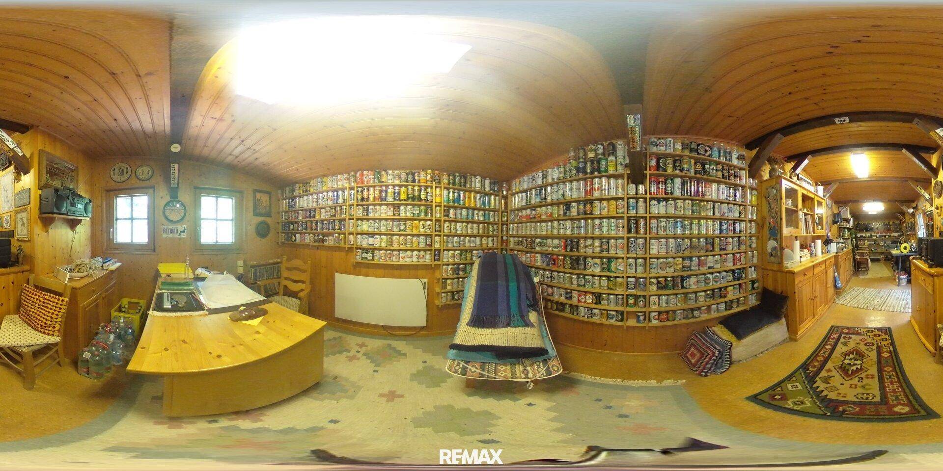 Geräumiges Büro oder Hobbyraum mit Holzvertäfelung, Regalen und einem großen Schreibtisch.
