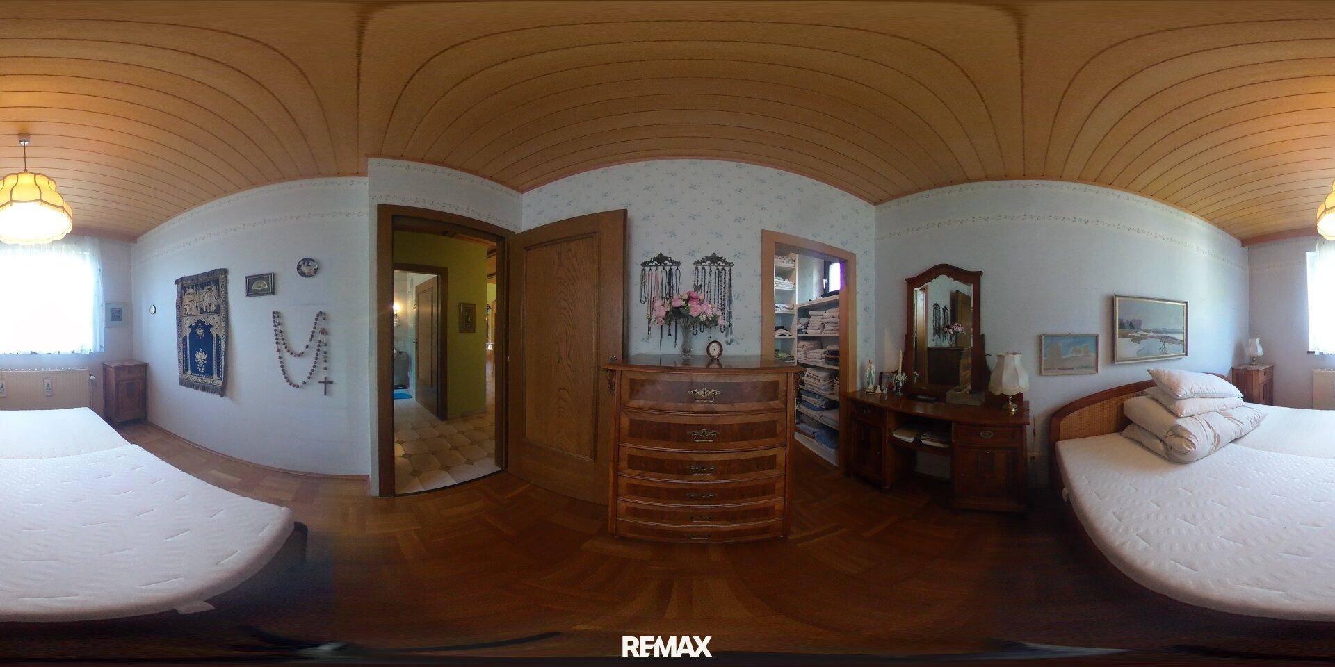 Gemütliches Schlafzimmer mit zwei Betten, Holzparkettboden und gewölbter Holzdecke.
