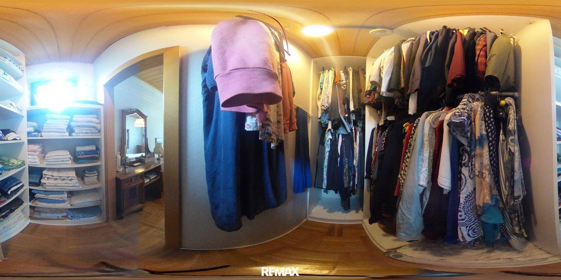 Begehbarer Kleiderschrank mit vielen Regalen und Aufhängemöglichkeiten für Kleidung.
