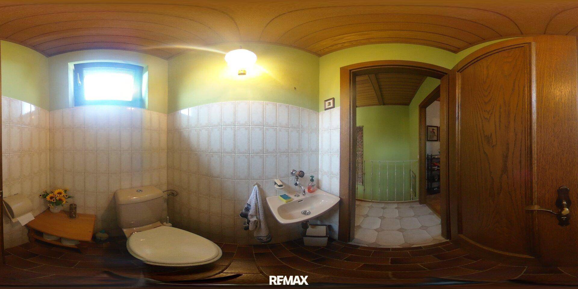 Kleines Gäste-WC mit hellgrünen Wänden, weißen Fliesen und gewölbter Holzdecke.