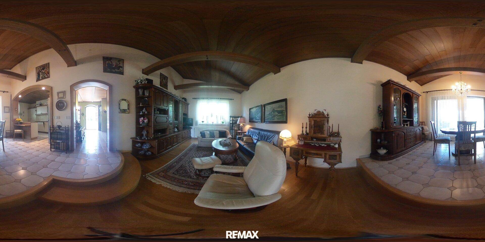 Traditionelles Wohnzimmer mit dunklen Holzmöbeln, Teppich und gewölbter Holzdecke.