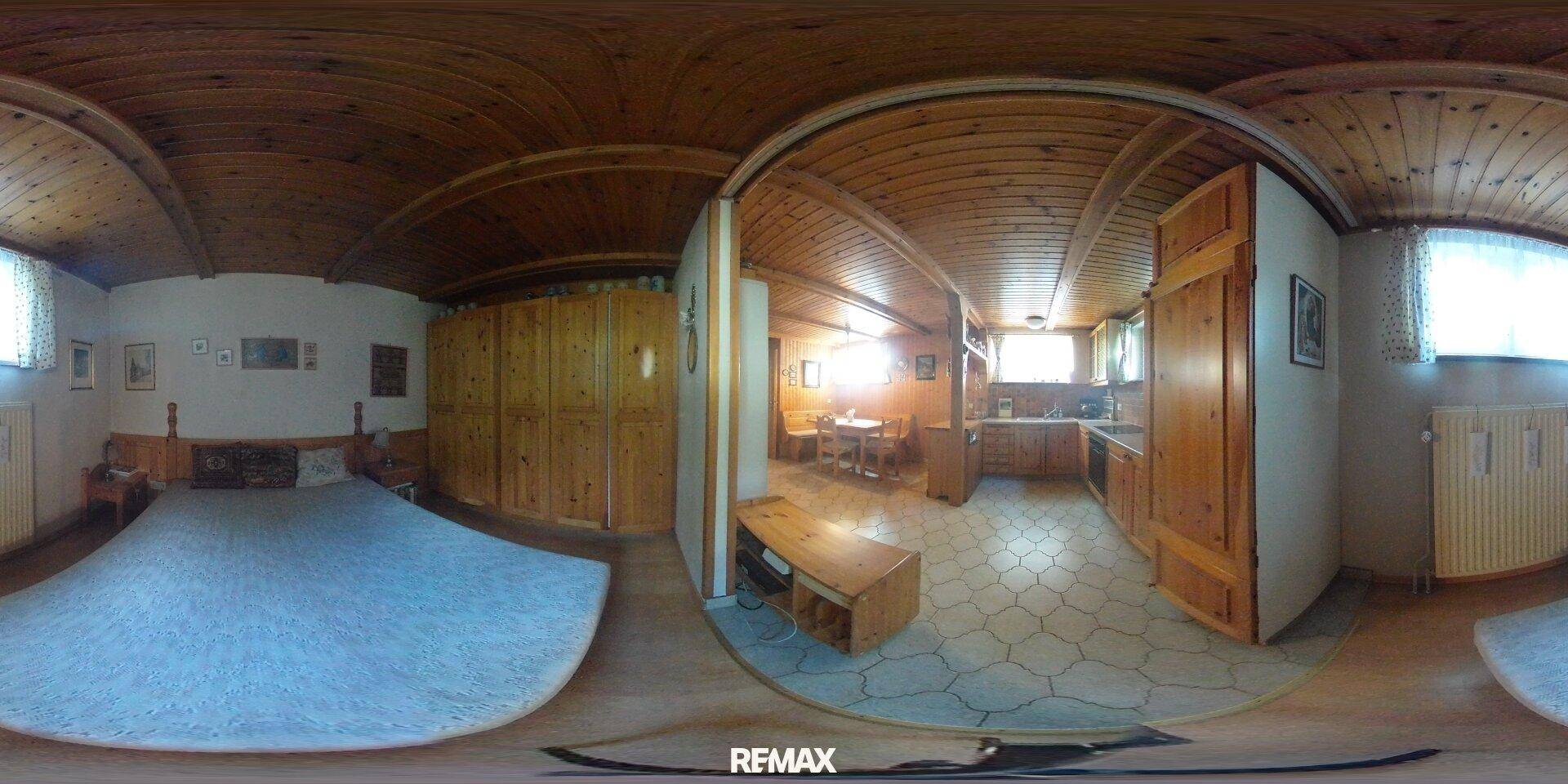 Schlafzimmer mit Bett, eingebauten Holzschränken und integriertem Küchenbereich.