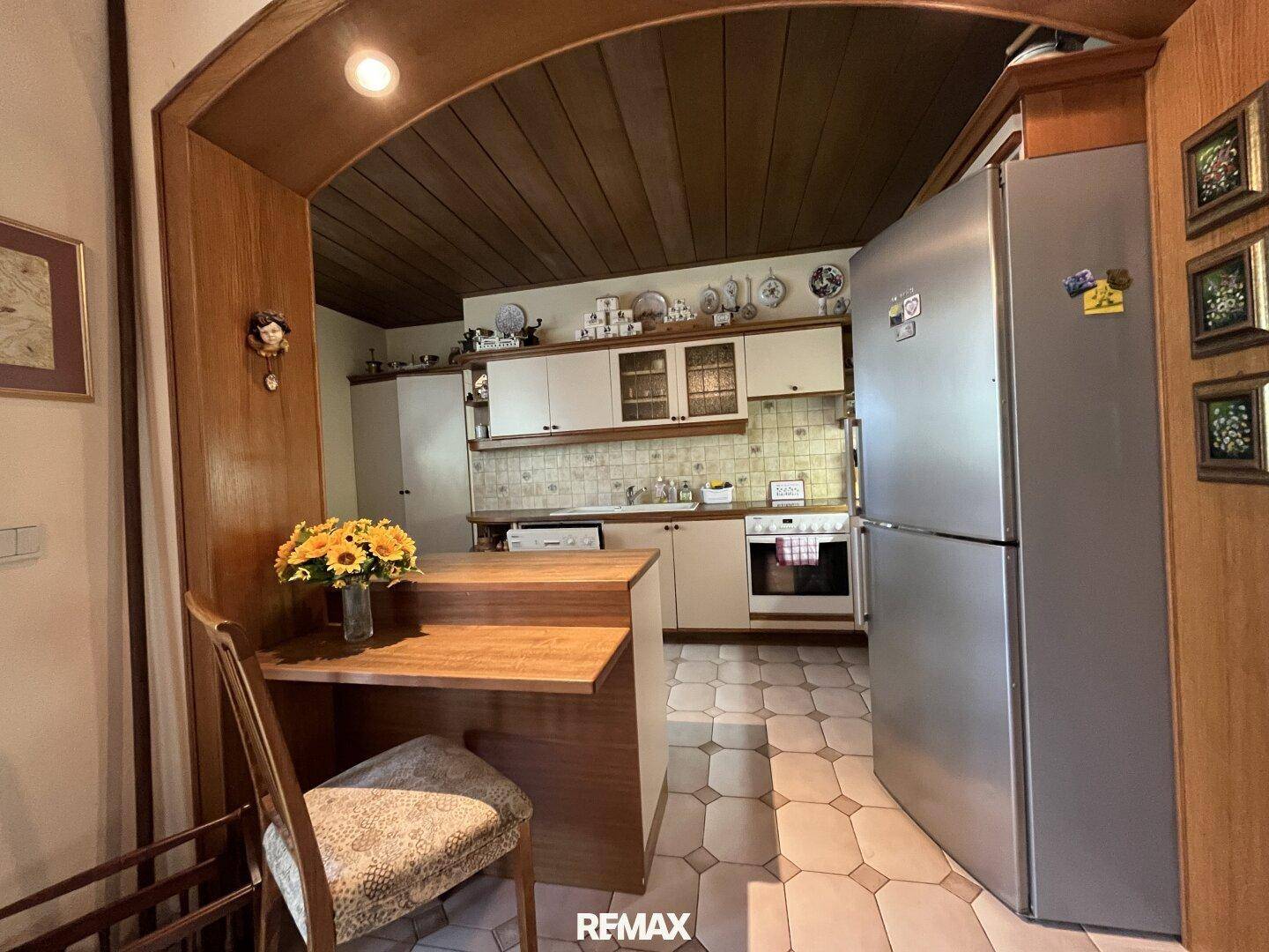 Traditionelle Küche mit Holzdecke, Einbauküche und Essbereich, gemütlich und funktional.