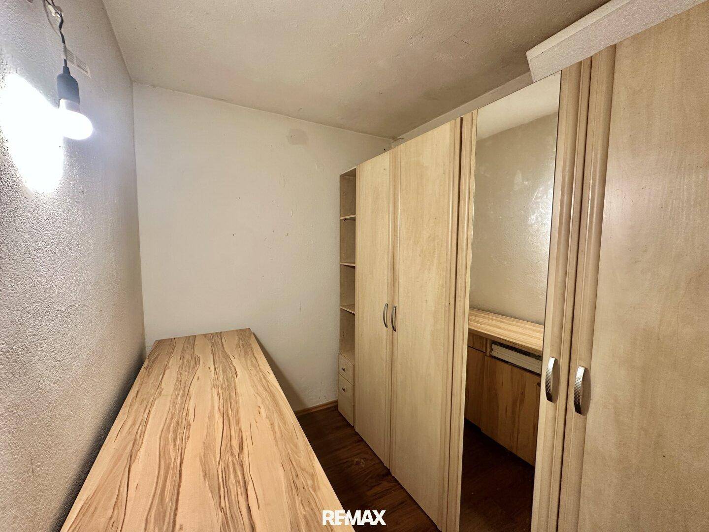 Kleiner Raum mit Holzboden, Einbauschränken und einer langen Holzablage.