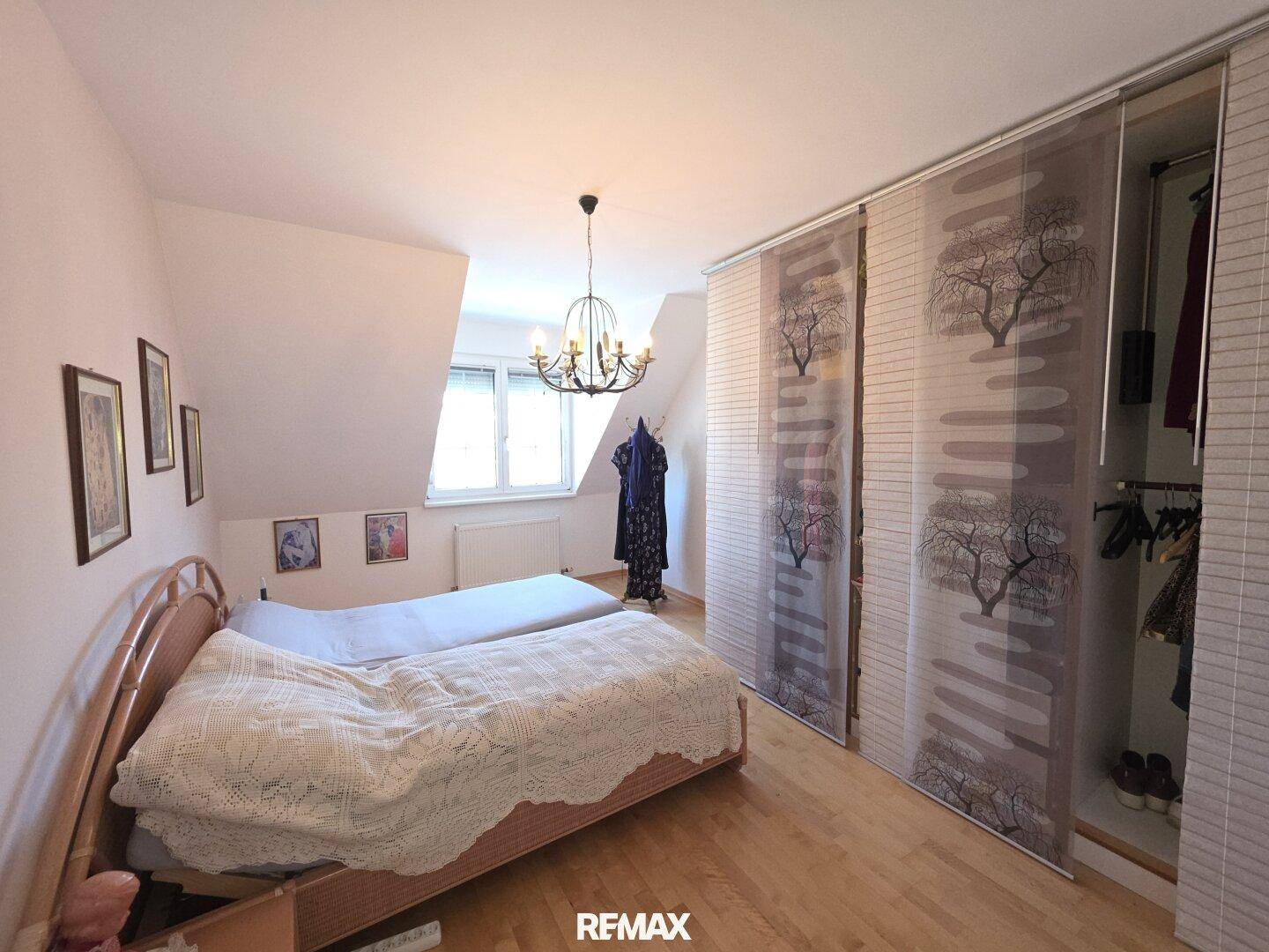 Schlafzimmer mit Doppelbett, Holzboden, Dachschräge und praktischen Schiebetürenschränken.