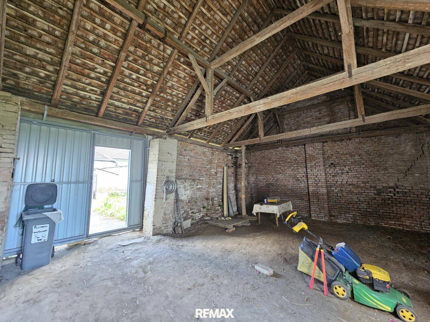 Geräumige Scheune mit offenem Holzdachstuhl und Ziegelwänden.