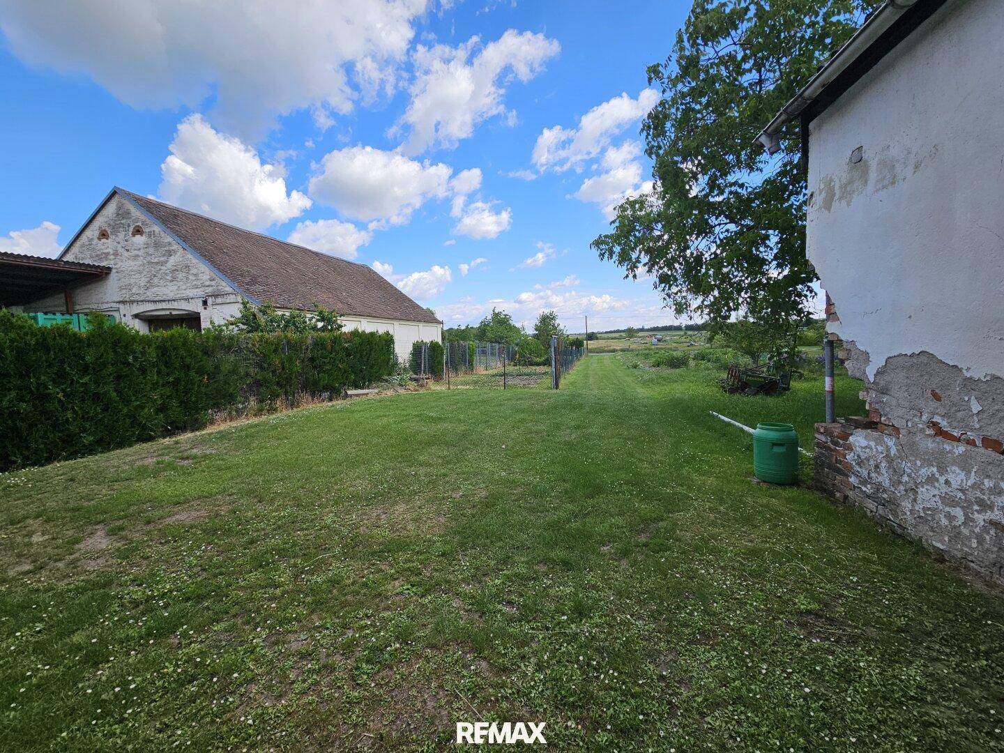 Großer Garten mit Rasenfläche, Hecke und weitem Blick in die Landschaft.