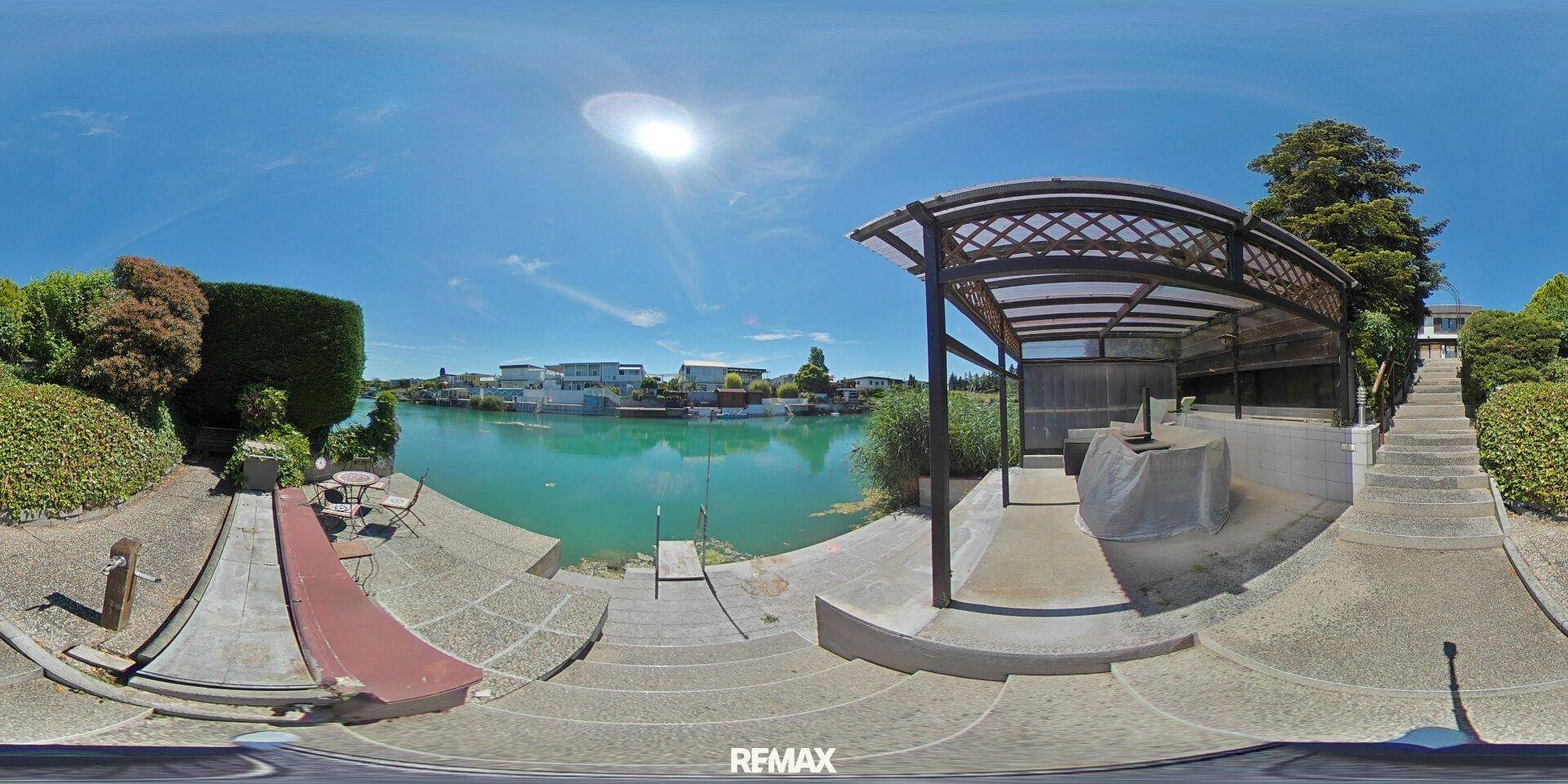 Uferbereich mit überdachtem Sitzplatz, Treppen zum Wasser und einer Rutsche.