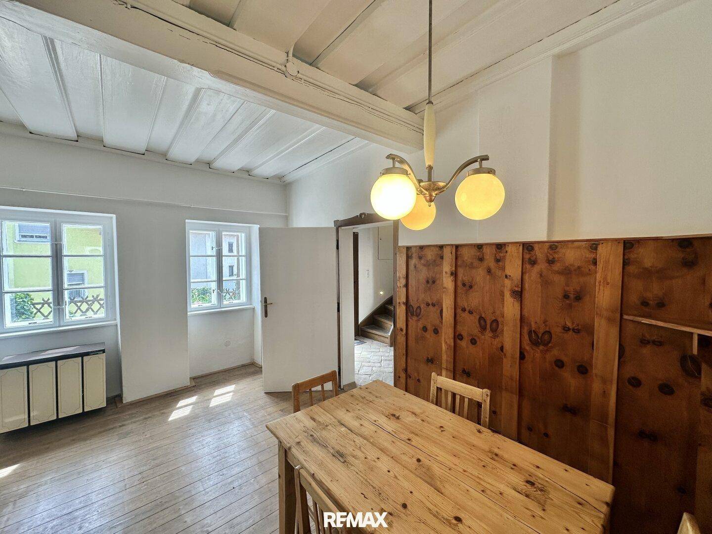Heller Essbereich mit Holzboden, Holztisch und Fenstern, die viel Tageslicht hereinlassen.
