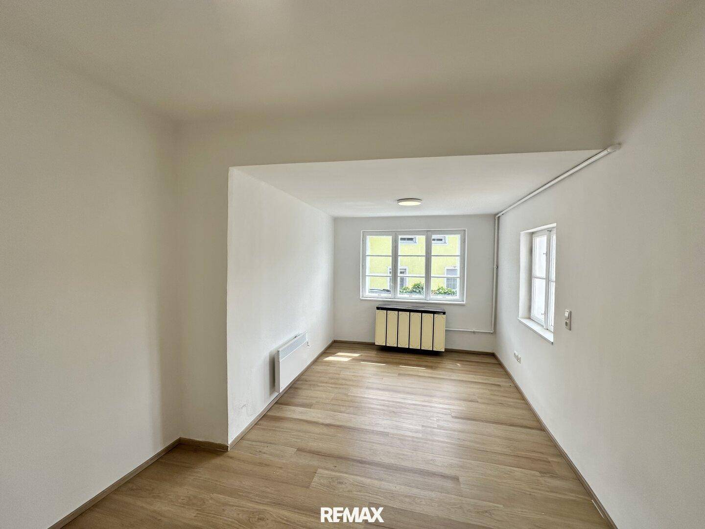 Helles Zimmer mit modernem Laminatboden und großen Fenstern, die für viel Tageslicht sorgen.
