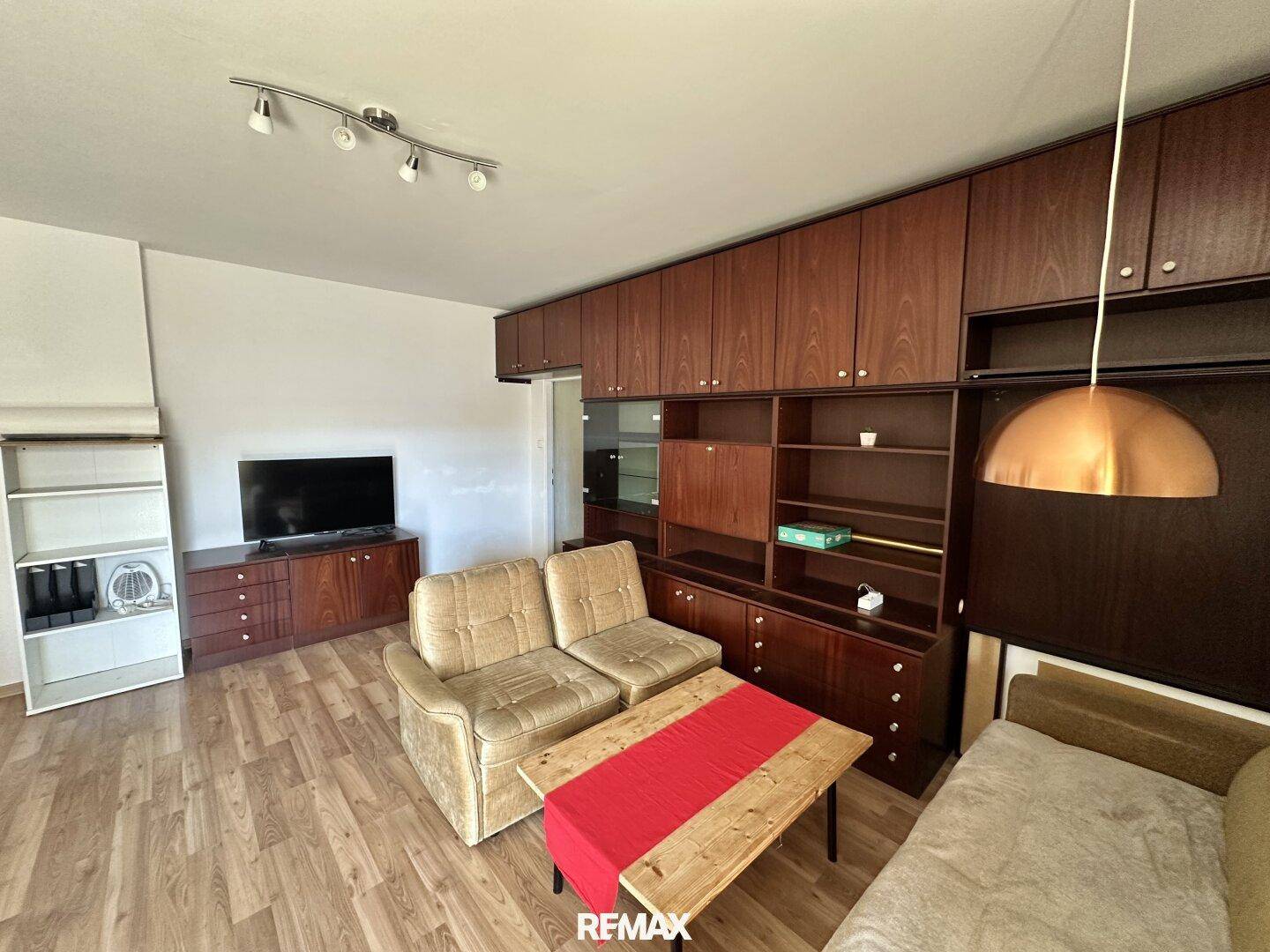 Wohnzimmer mit Laminatboden und umfangreicher Holzschrankwand, bietet viel Stauraum und eine gemütliche Atmosphäre.