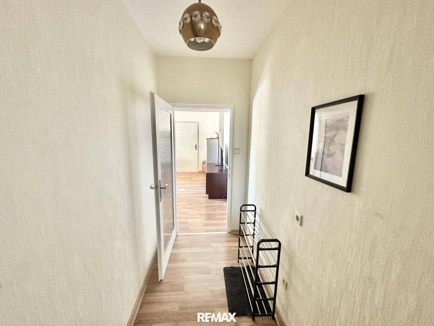 Heller Flur mit Laminatboden und Schuhregal, führt zu weiteren Räumen der Wohnung.