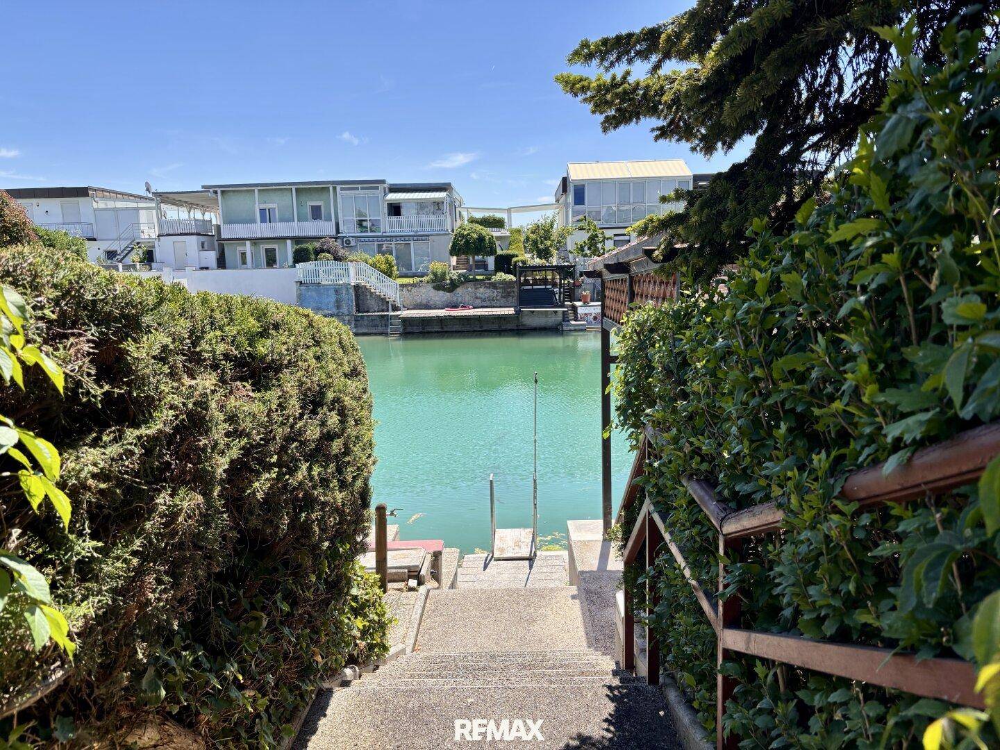 Treppe führt durch üppiges Grün direkt zu einem ruhigen See oder Kanal.