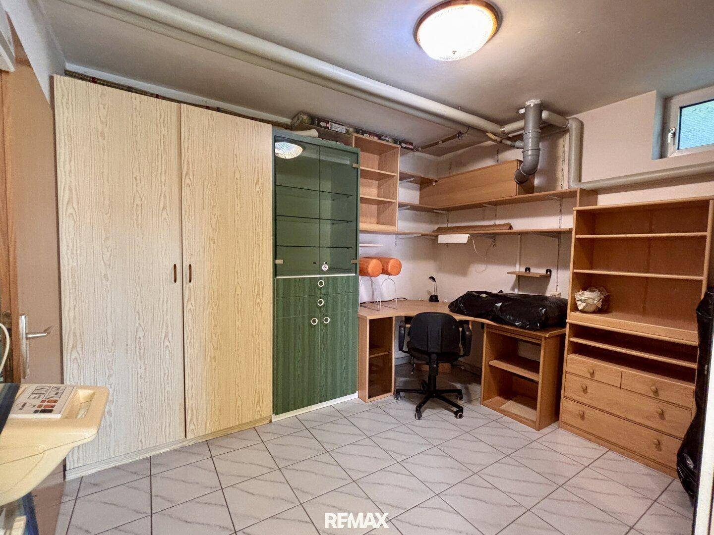 Geräumiger Kellerraum mit Fliesenboden, Schränken und Schreibtisch, vielseitig nutzbar.