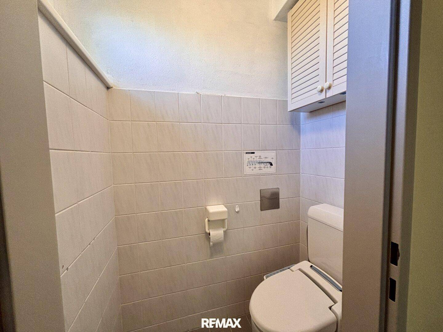 Kleines Gäste-WC mit gefliesten Wänden und einer Toilette mit Spülkasten.