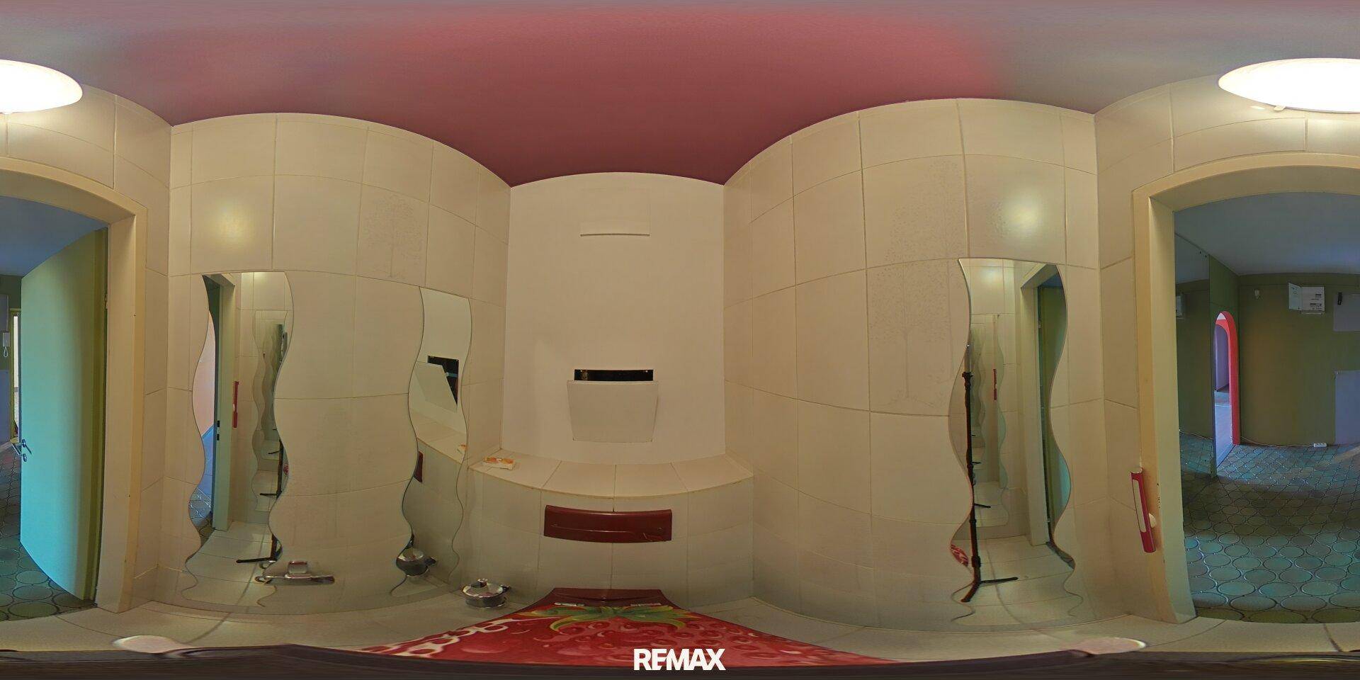 Panoramaansicht eines kleinen WCs mit weißen Fliesen, Erdbeer-Toilettensitz und wellenförmigen Spiegeln.