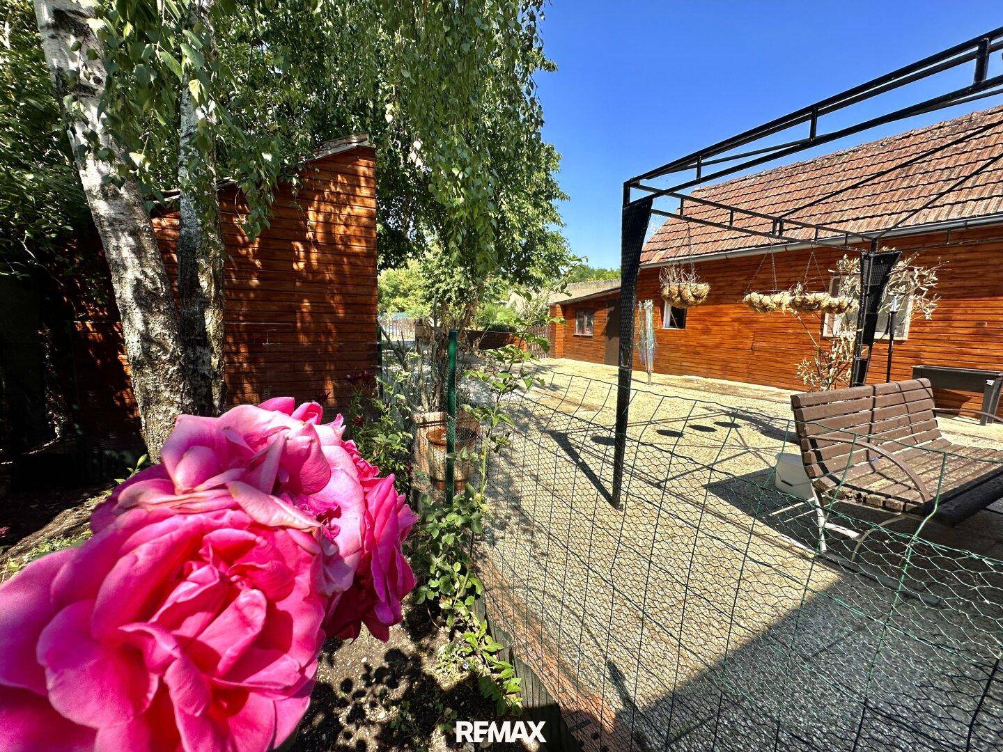 Blühender Garten mit Rosen, Gartenhaus und überdachtem Sitzbereich, bietet viel Privatsphäre.