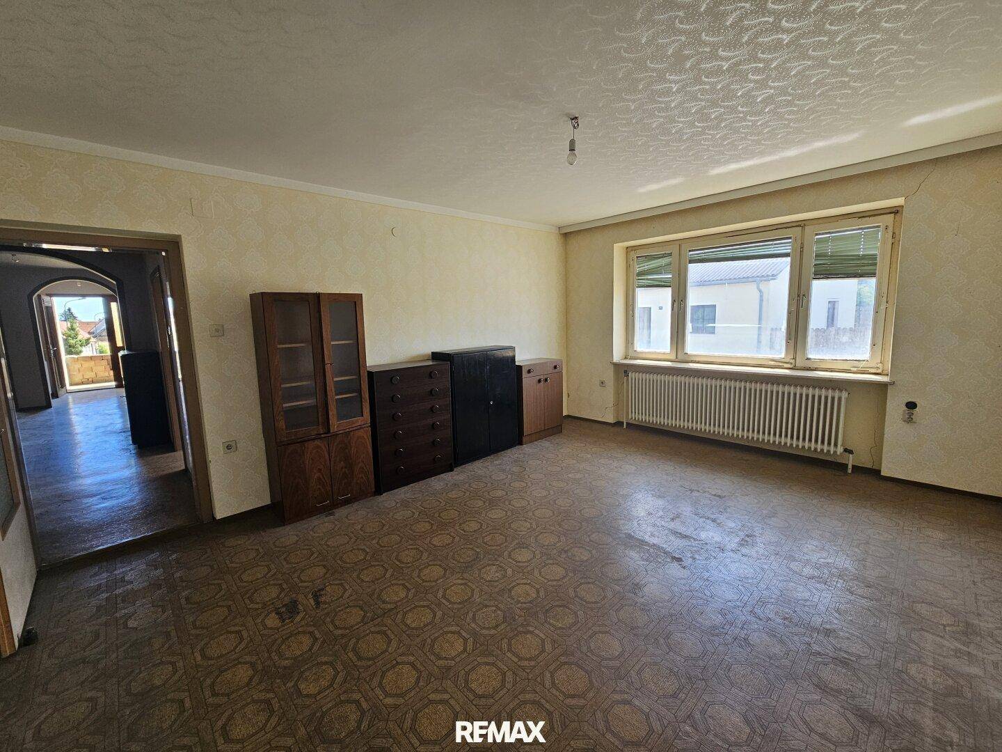 Wohnzimmer mit Terrazzoboden, traditionellen Möbeln und großem Fenster.