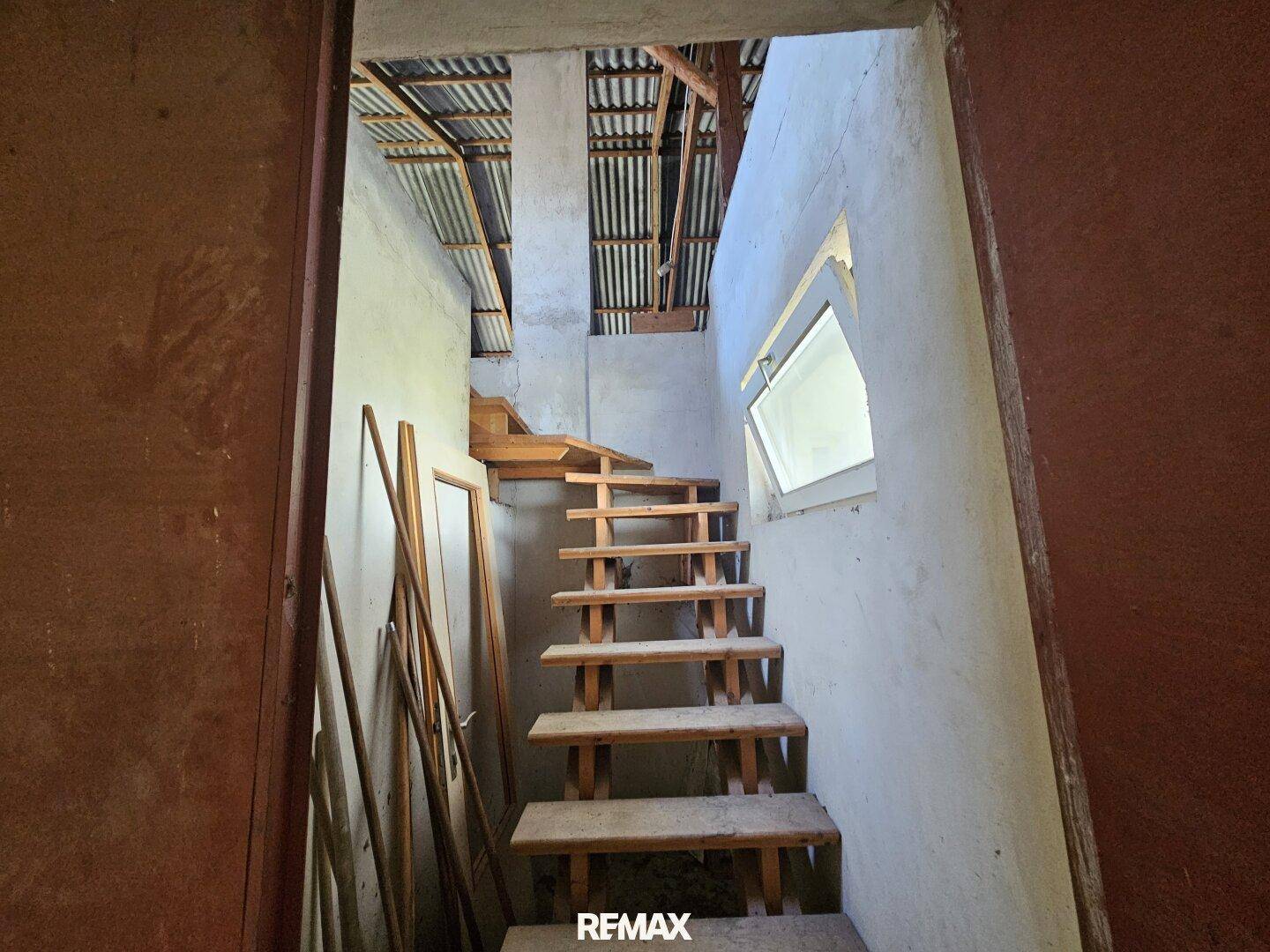 Holztreppe führt zum unfertigen Dachboden mit sichtbarer Dachkonstruktion.