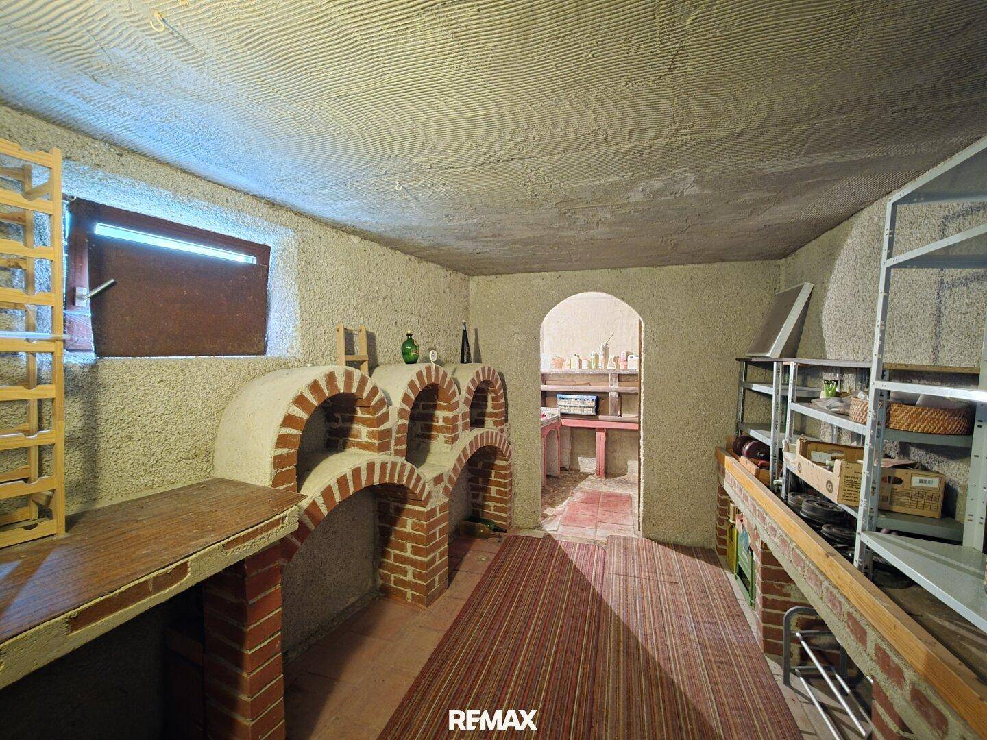 Traditioneller Kellerraum mit gemauerten Bögen und Regalen, ideal zur Lagerung.
