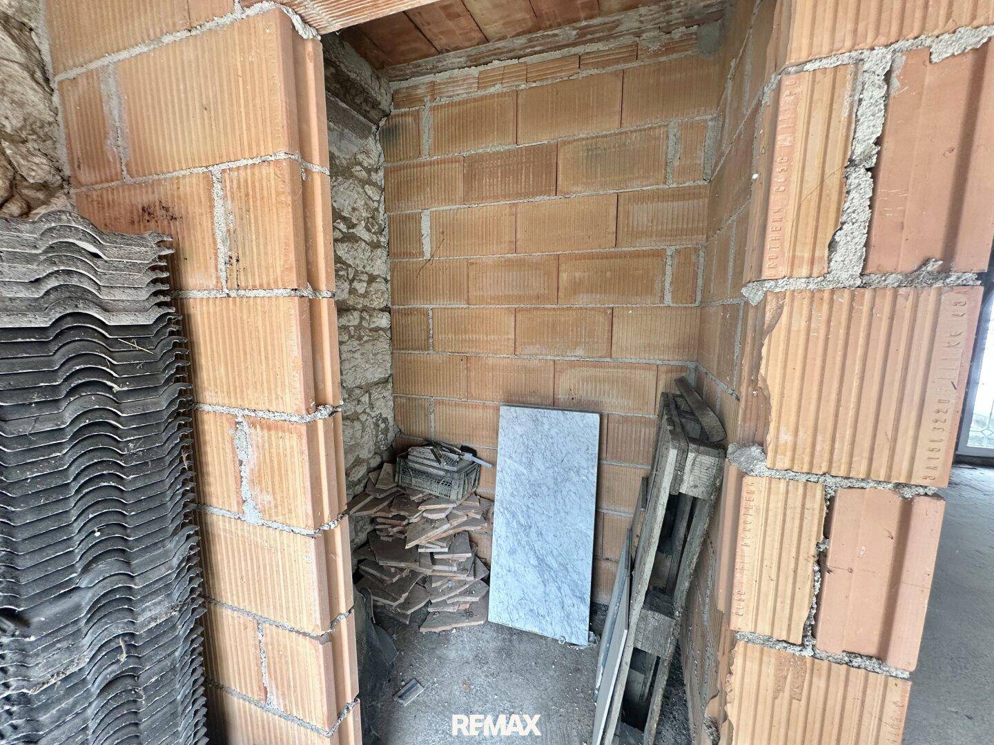 Nische im Rohbau mit Ziegelwänden und gelagerten Baumaterialien, bereit für den Ausbau.