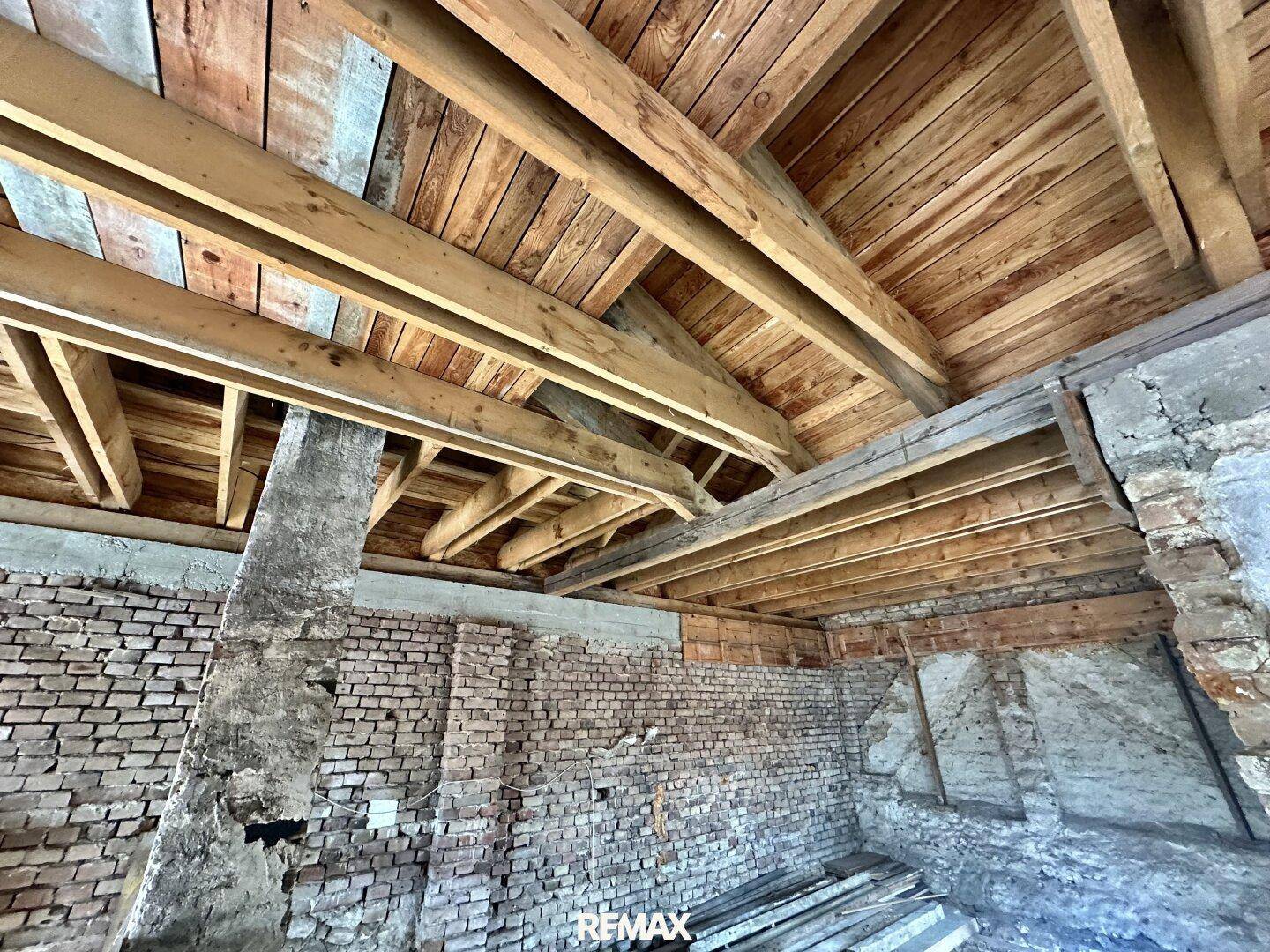 Blick auf den freiliegenden Holzdachstuhl, der die robuste Bauweise des Gebäudes zeigt.