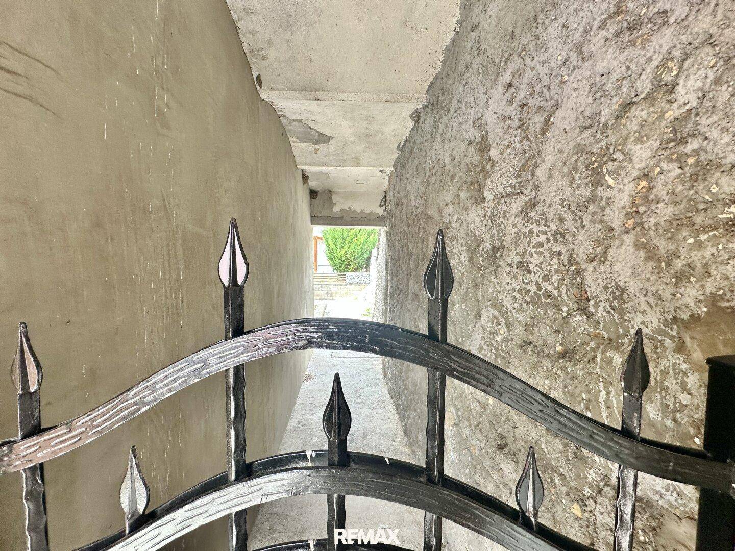 Schmaler Durchgang zwischen den Gebäuden mit schmiedeeisernem Tor.