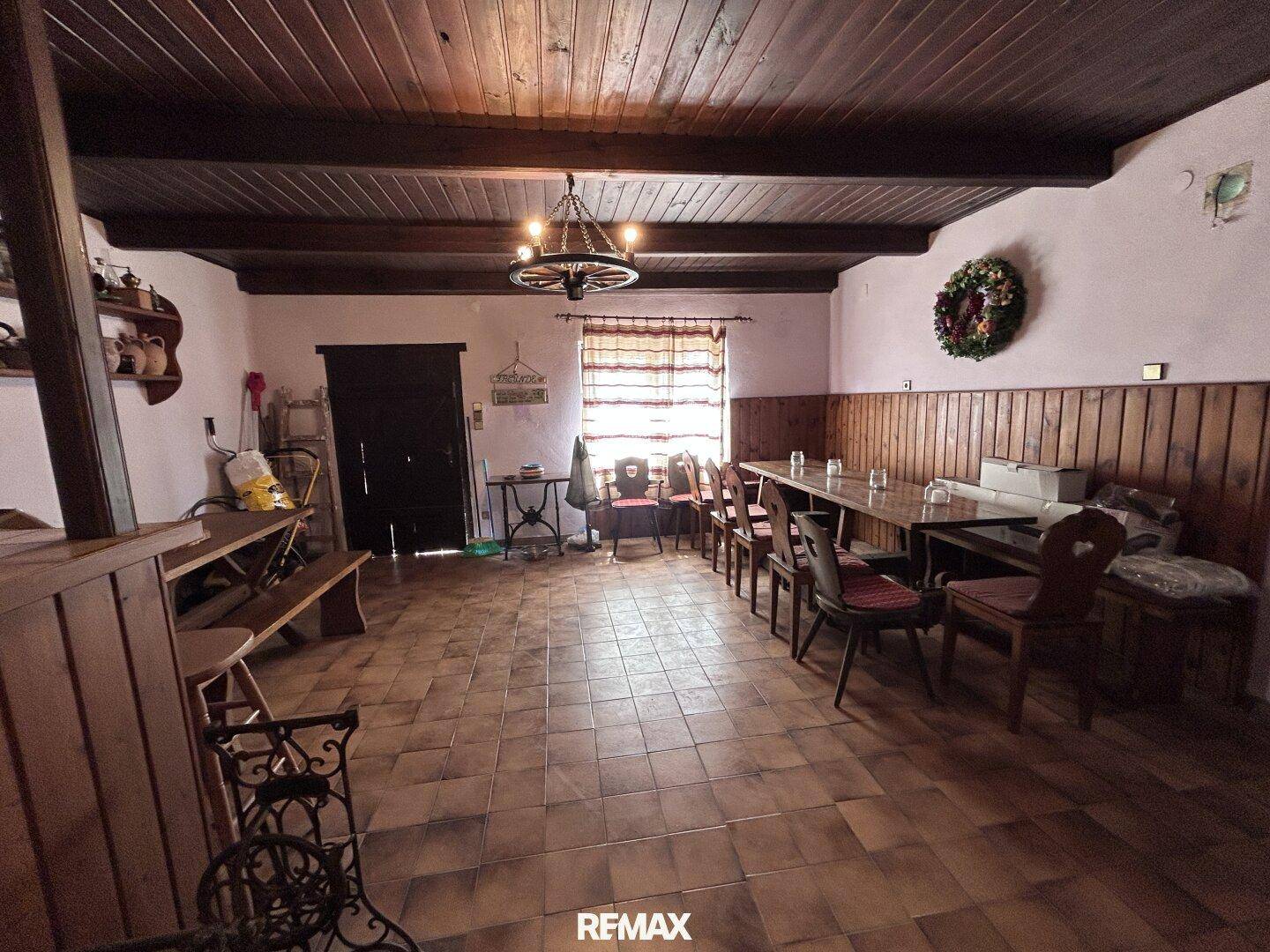 Geräumiger Essbereich im Landhausstil mit Holzbalken, langen Tischen und rustikalem Charme.