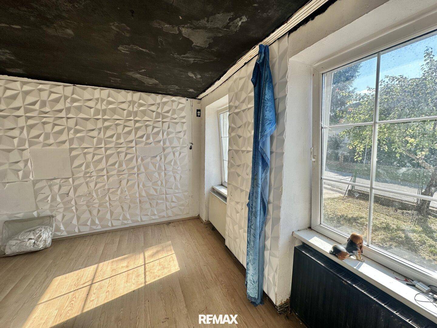 Helles Zimmer mit 3D-Wandverkleidung, dunkler Decke und großem Fenster.