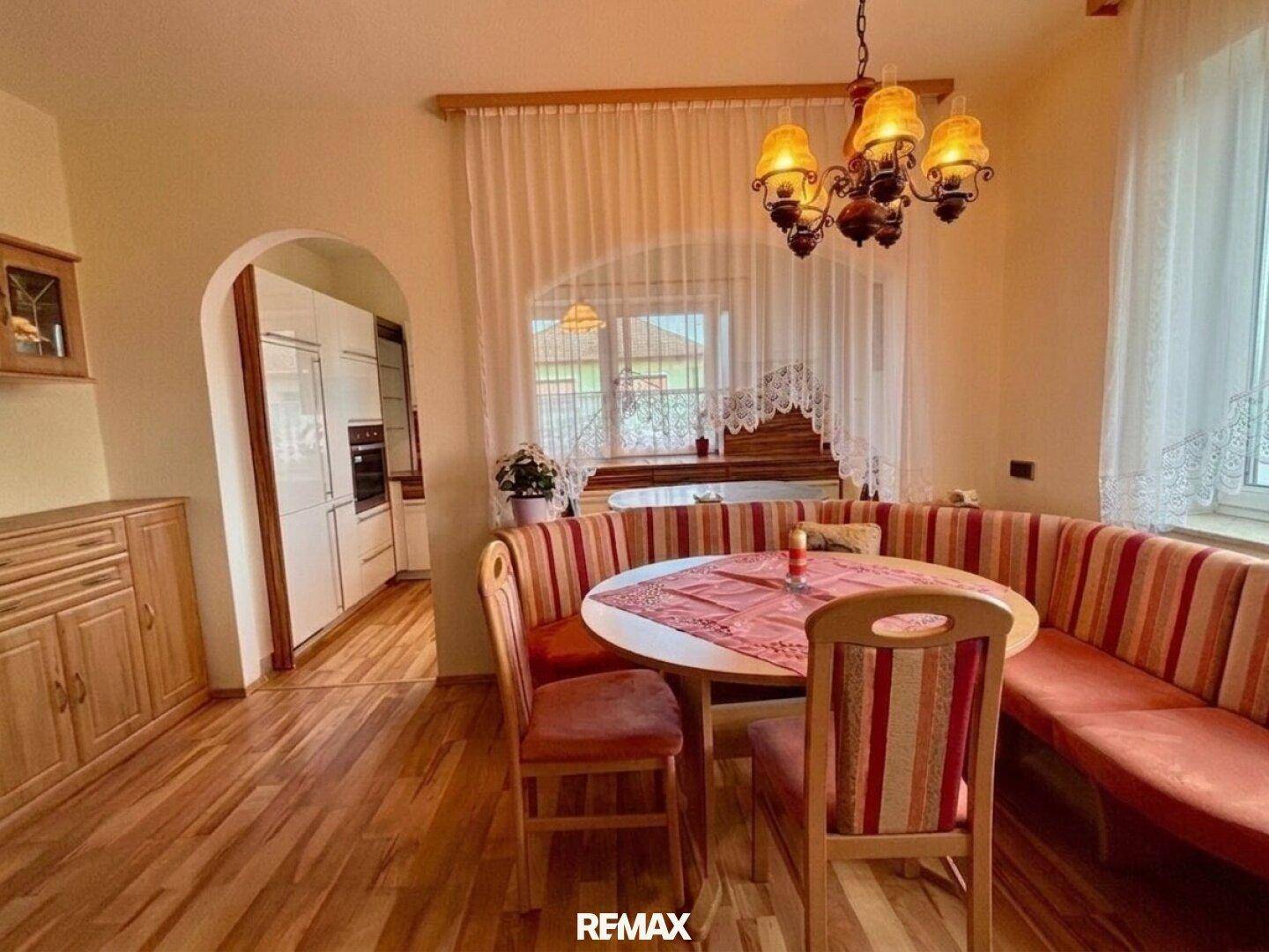 Gemütlicher Essbereich mit Holzboden und integrierter Sitzbank, angrenzend an eine moderne Küche.