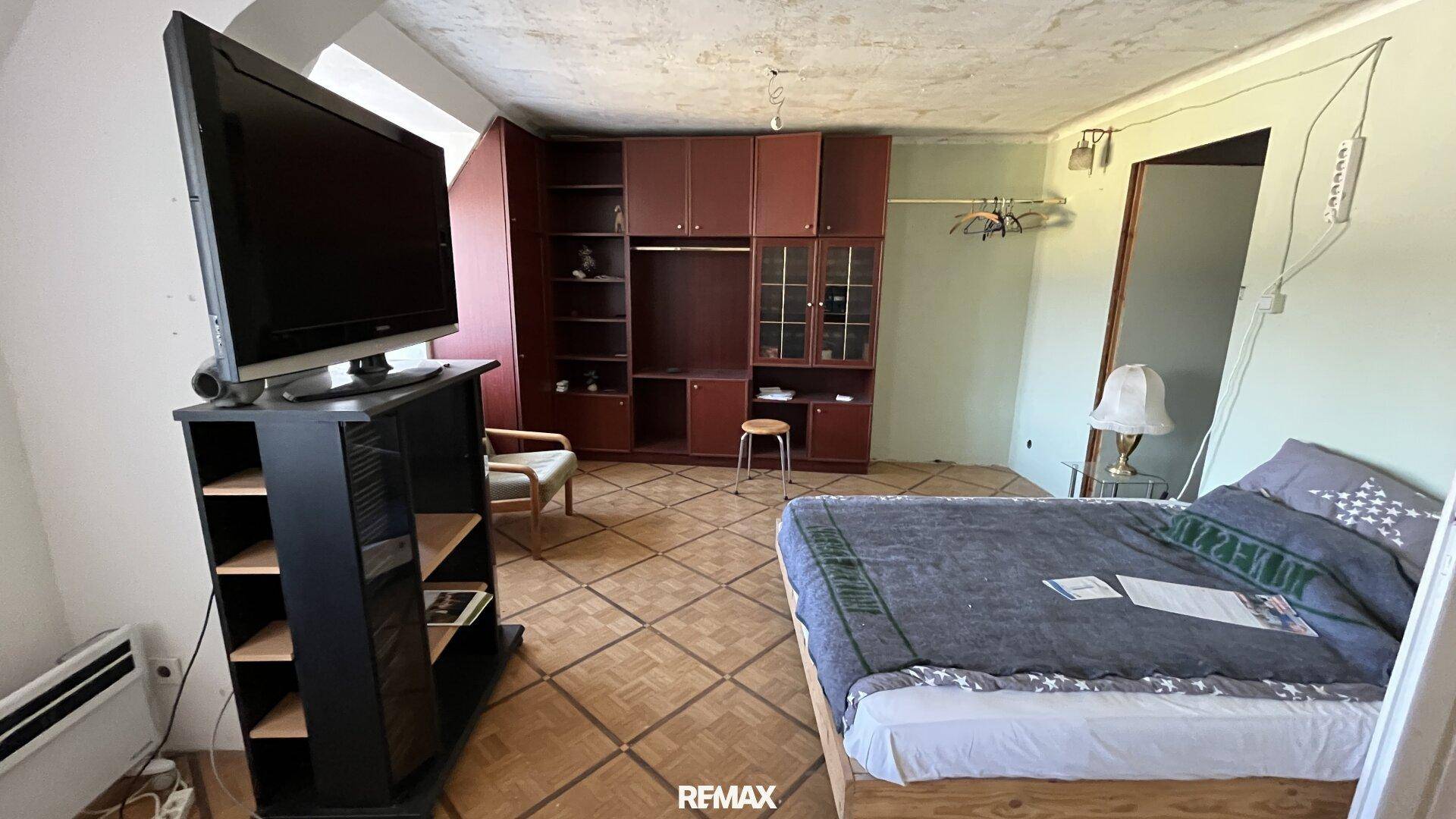 Schlafzimmer mit Bett, Fernseher und großem Kleiderschrank, der viel Stauraum bietet.