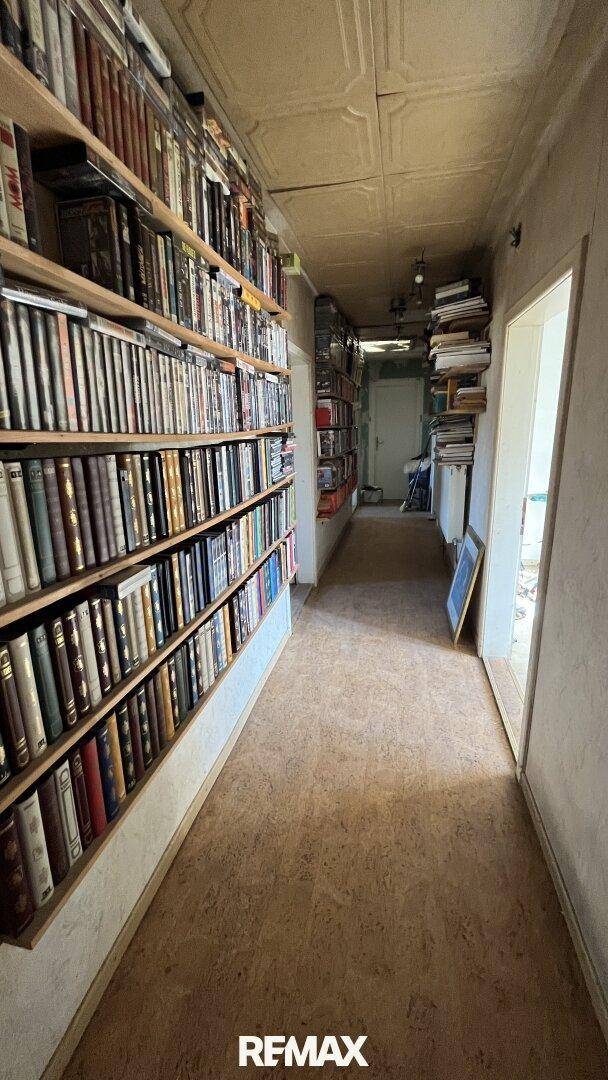 Langer Flur mit Bücherregalen entlang der Wand und Korkboden, der als Bibliothek dient.