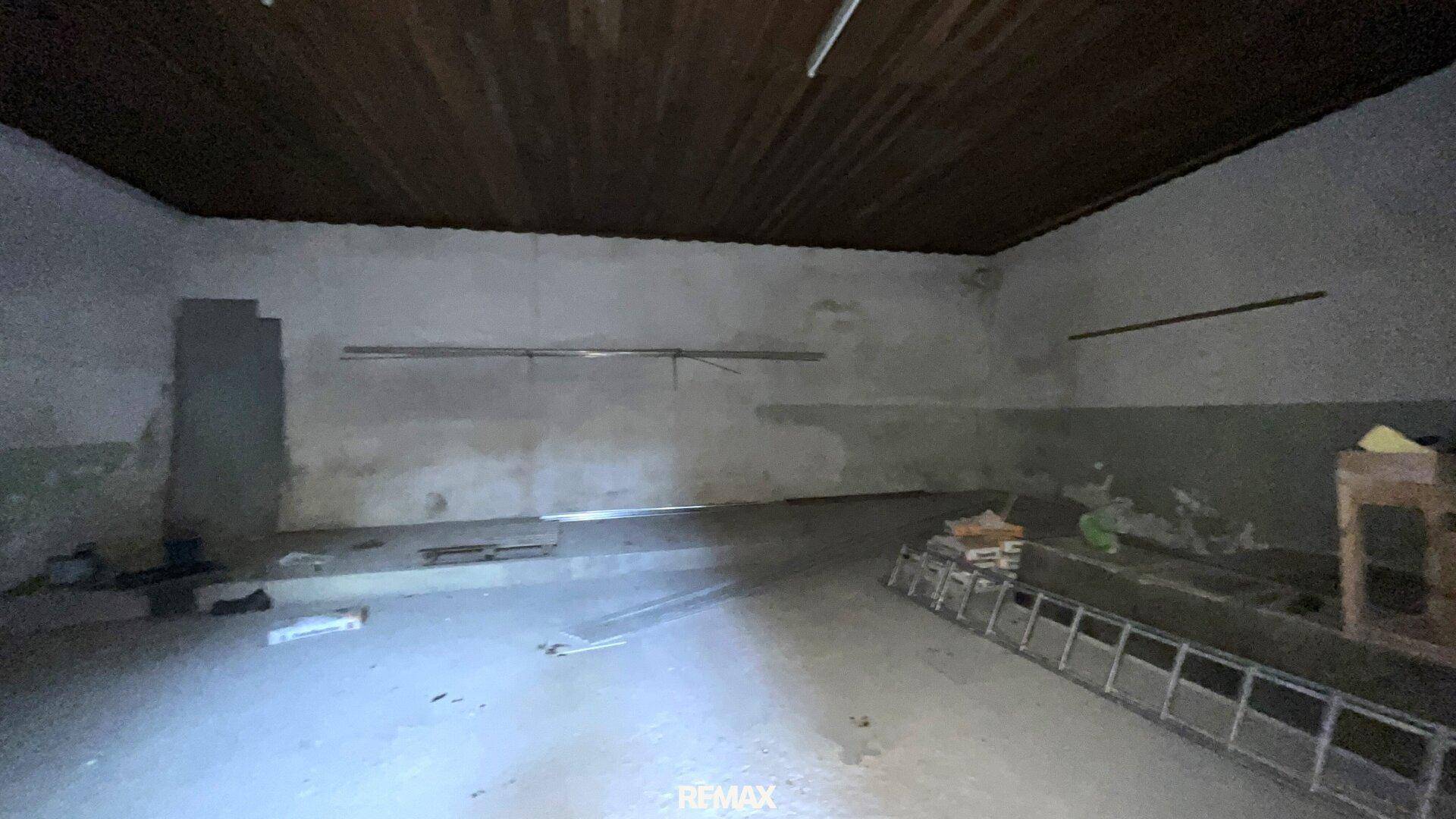 Großer, unfertiger Innenraum mit Betonboden und Holzdecke, bereit für den Ausbau.