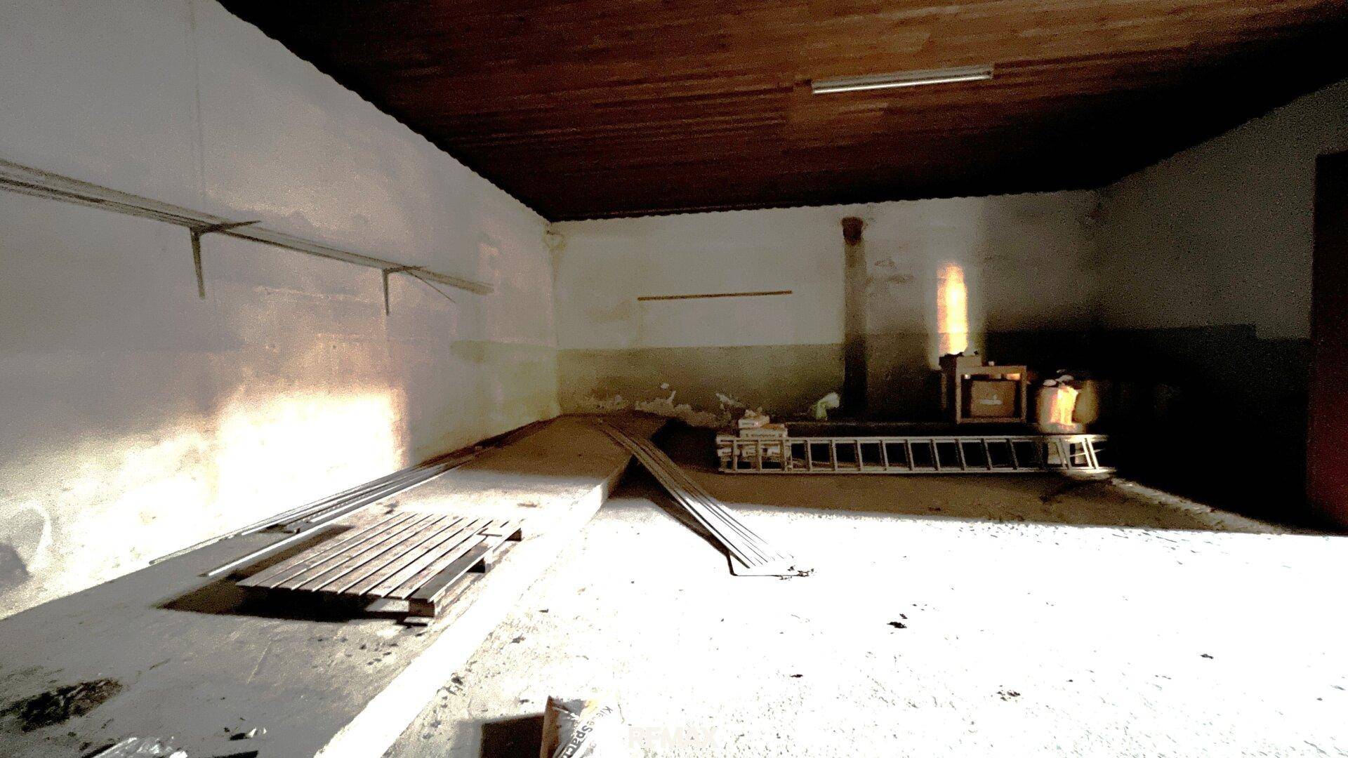 Heller, ungenutzter Innenraum mit Holzdecke und Betonboden, durch Sonnenlicht erhellt.