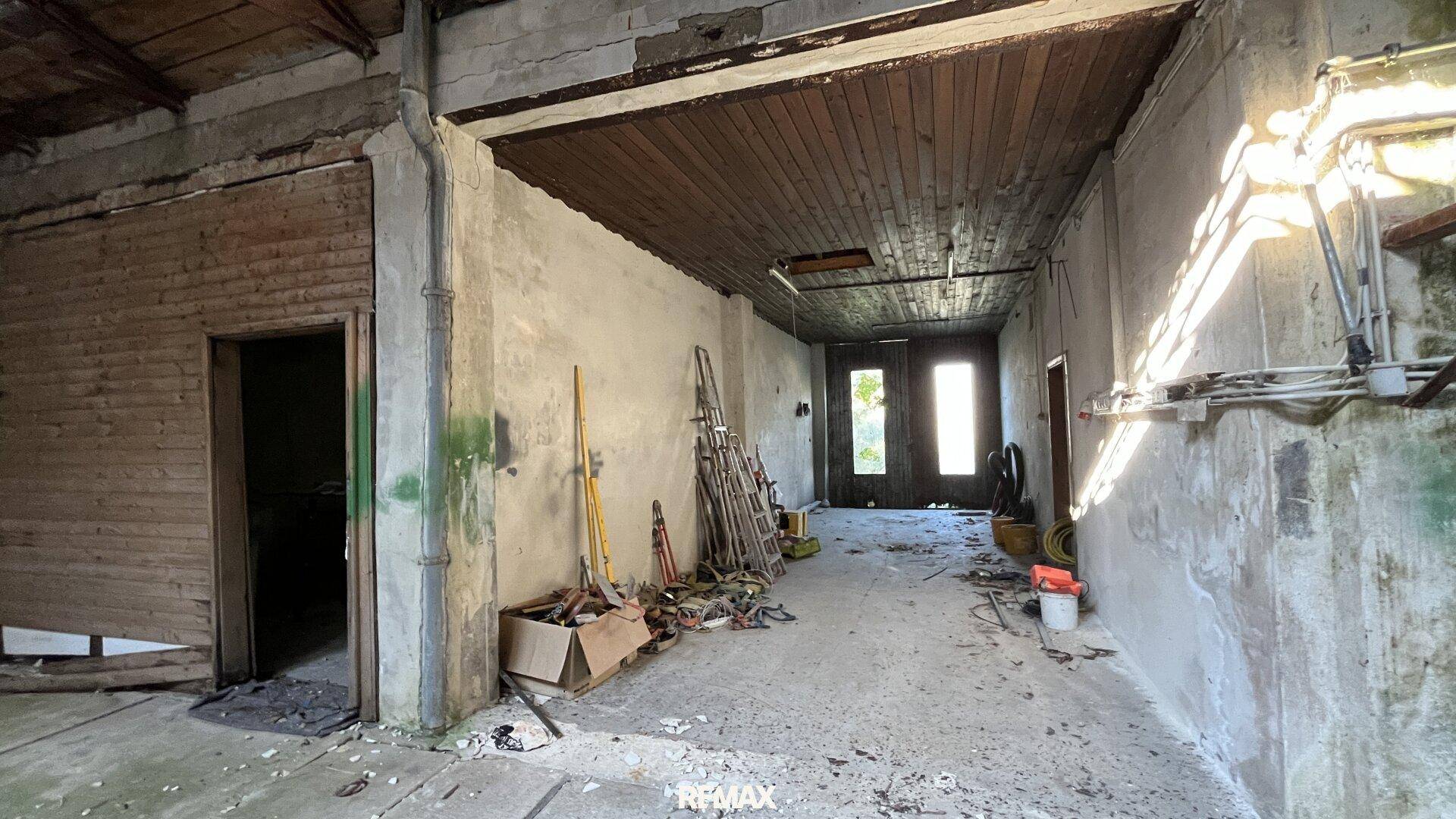 Langer, unfertiger Flur mit Holzdecke und Betonboden, führt zu weiteren Räumen.