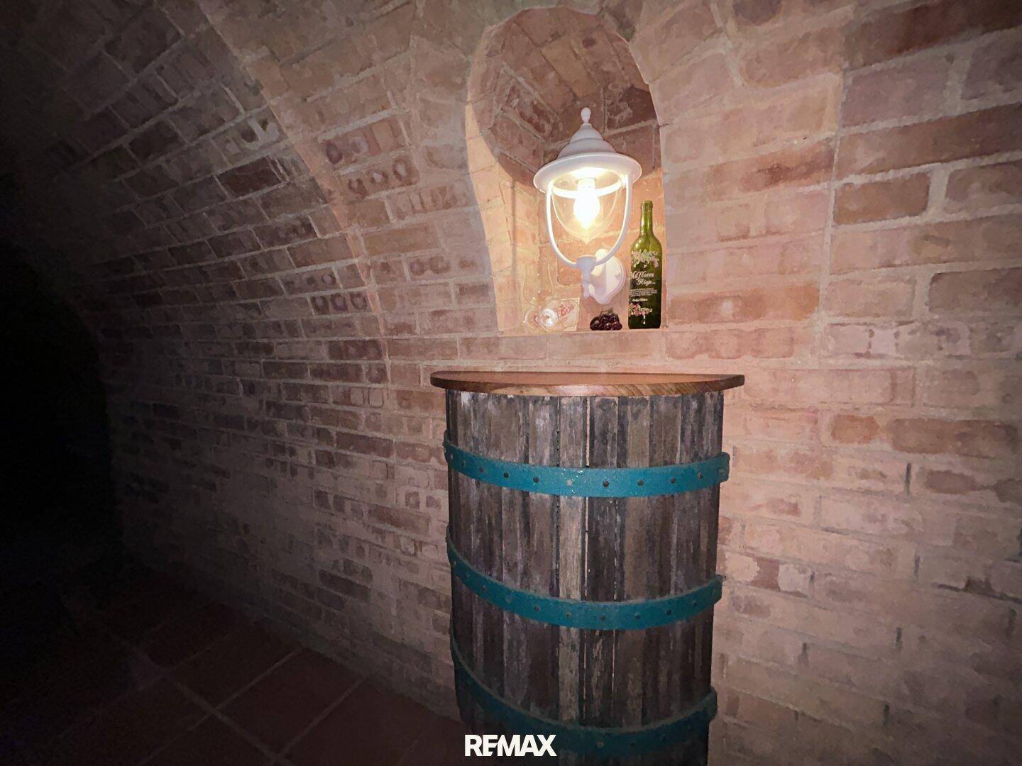Detailansicht eines Weinfasses als Tisch mit Lampe und Weinflasche im Ziegelkeller.