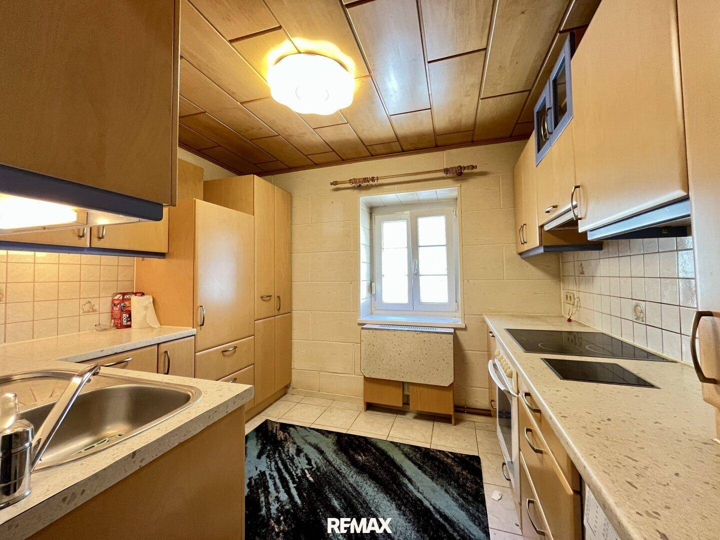 Helle Küche mit Holzdecken, Fliesenboden und einem Fenster für natürliches Licht.
