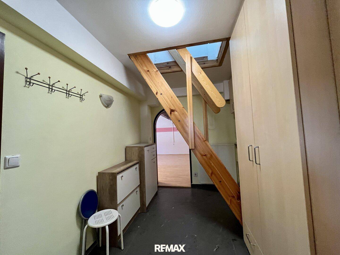 Eingangsbereich mit Garderobe, Schränken und einer Holztreppe zum Obergeschoss.