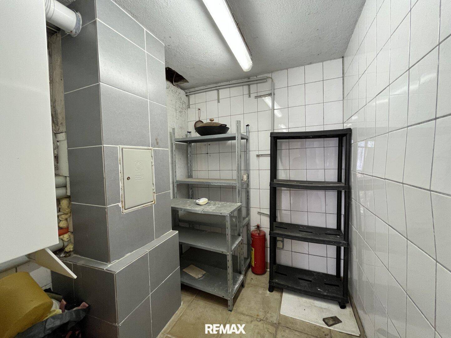Hauswirtschaftsraum mit Regalen, Fliesenwänden und einem Feuerlöscher.