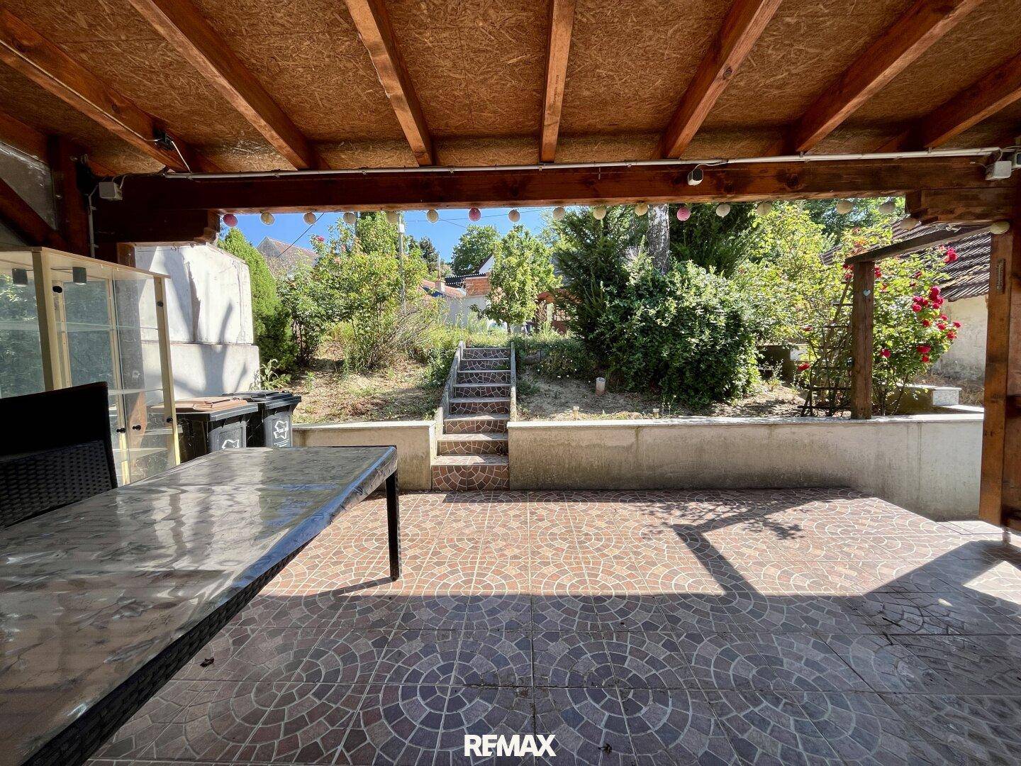 Geräumige überdachte Terrasse mit Fliesenboden und einem großen Esstisch.